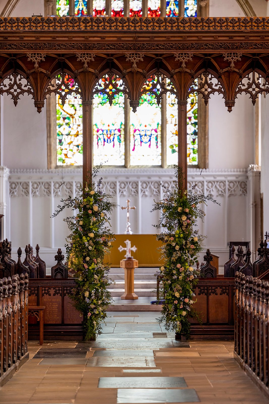 Interior view of a church decorated for a wedding with floral arrangements and stained glass windows.