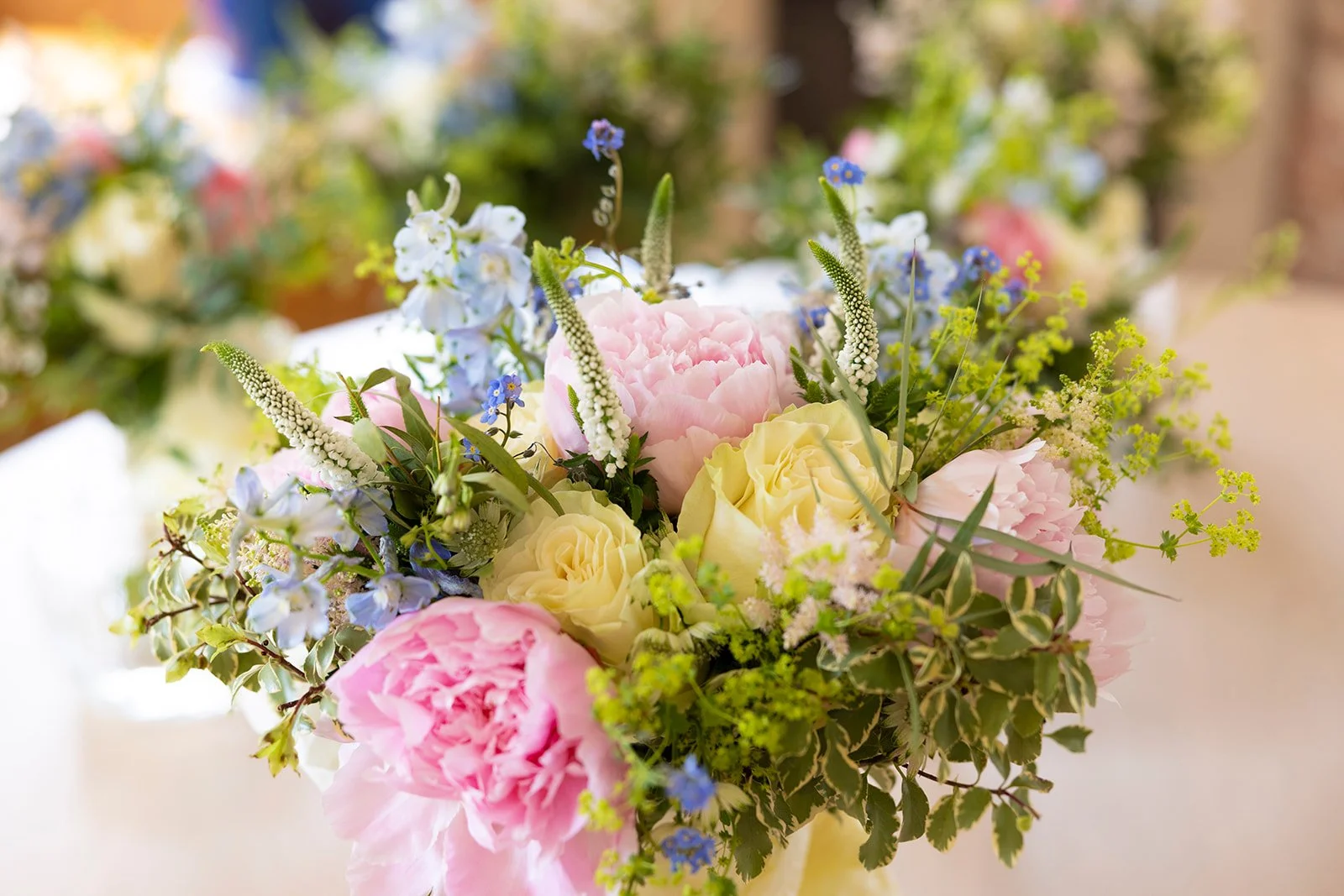 A bouquet of pink, yellow, white, and blue flowers with green foliage.