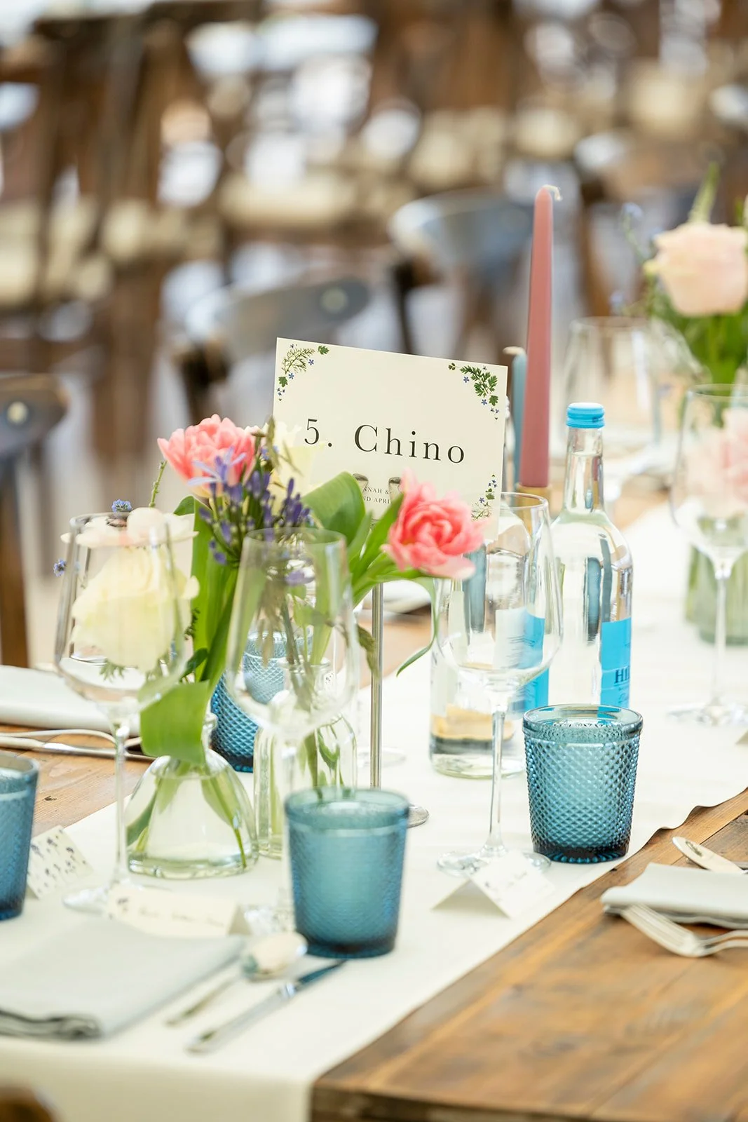 Table decorated with pink and purple flowers, blue glasses, and a sign labeled '5. Chino'.