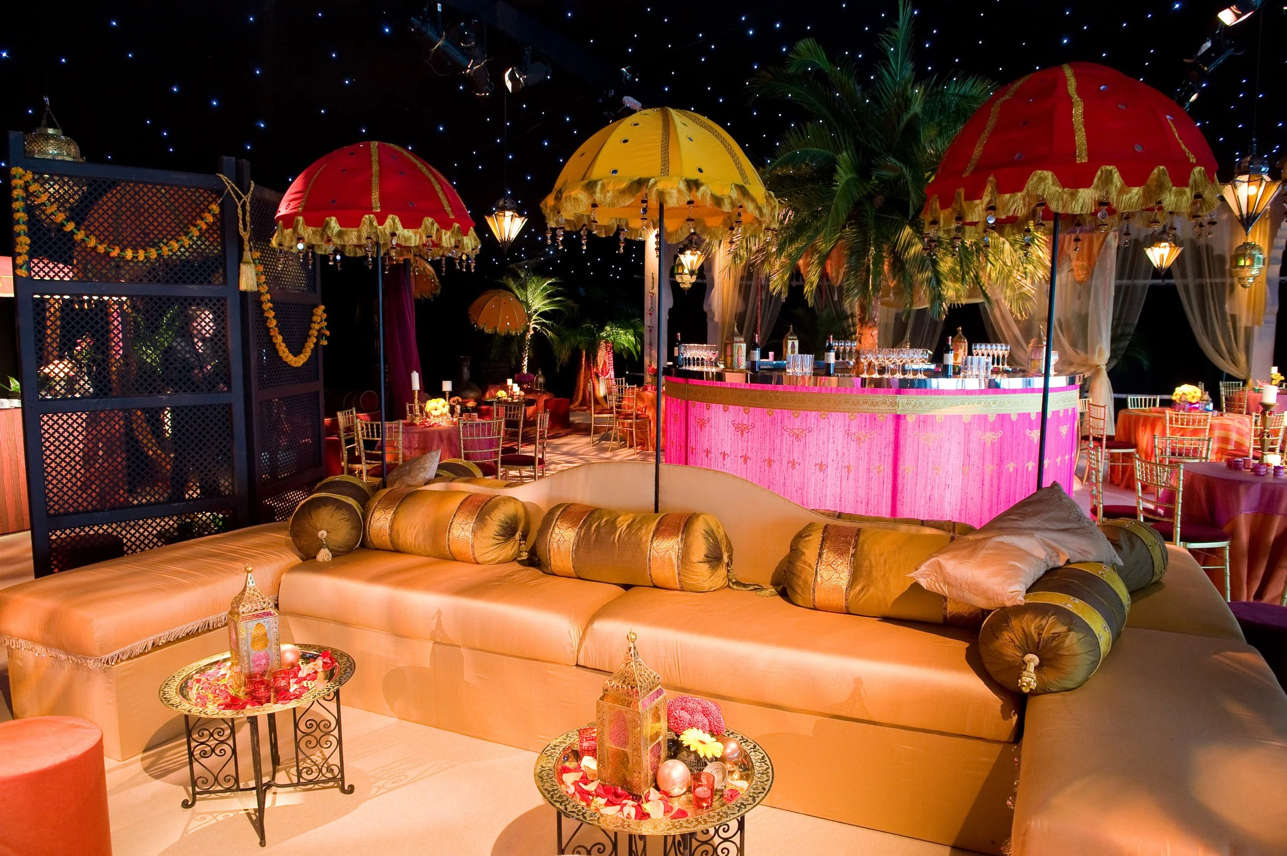Colorful lounge area decorated with vibrant umbrellas hanging from the ceiling, soft lighting, and elegant furniture, creating a festive atmosphere.