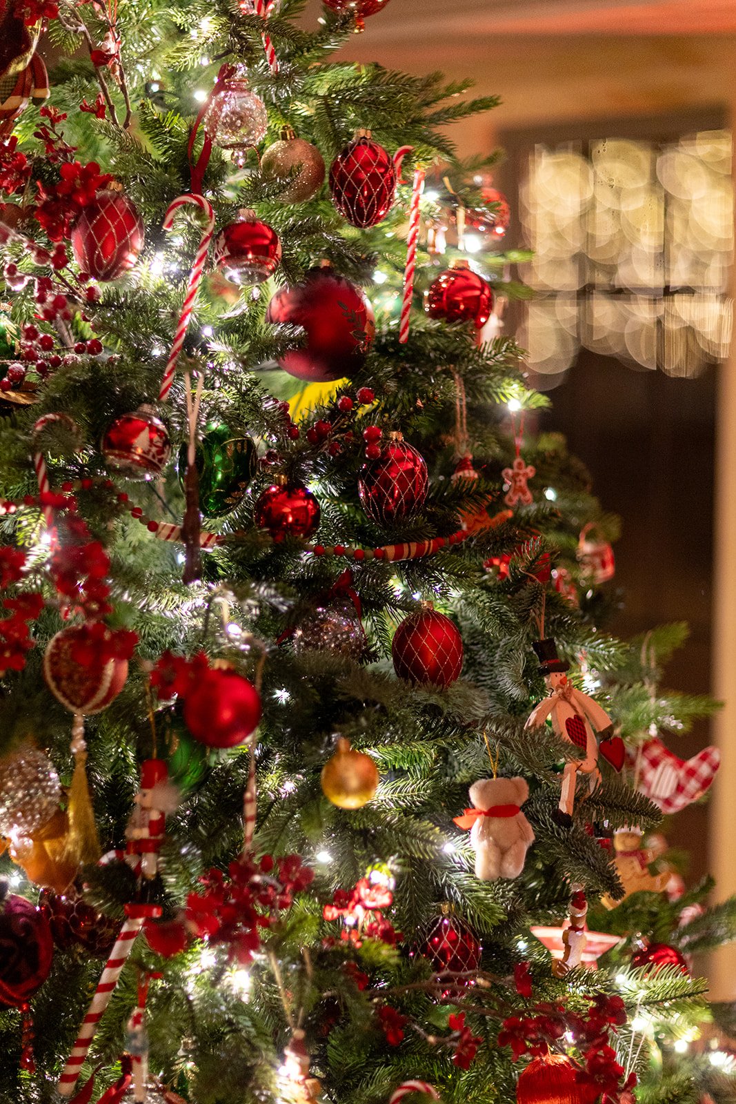 Decorated Christmas tree with red, gold, and green ornaments, candy canes, and lights.