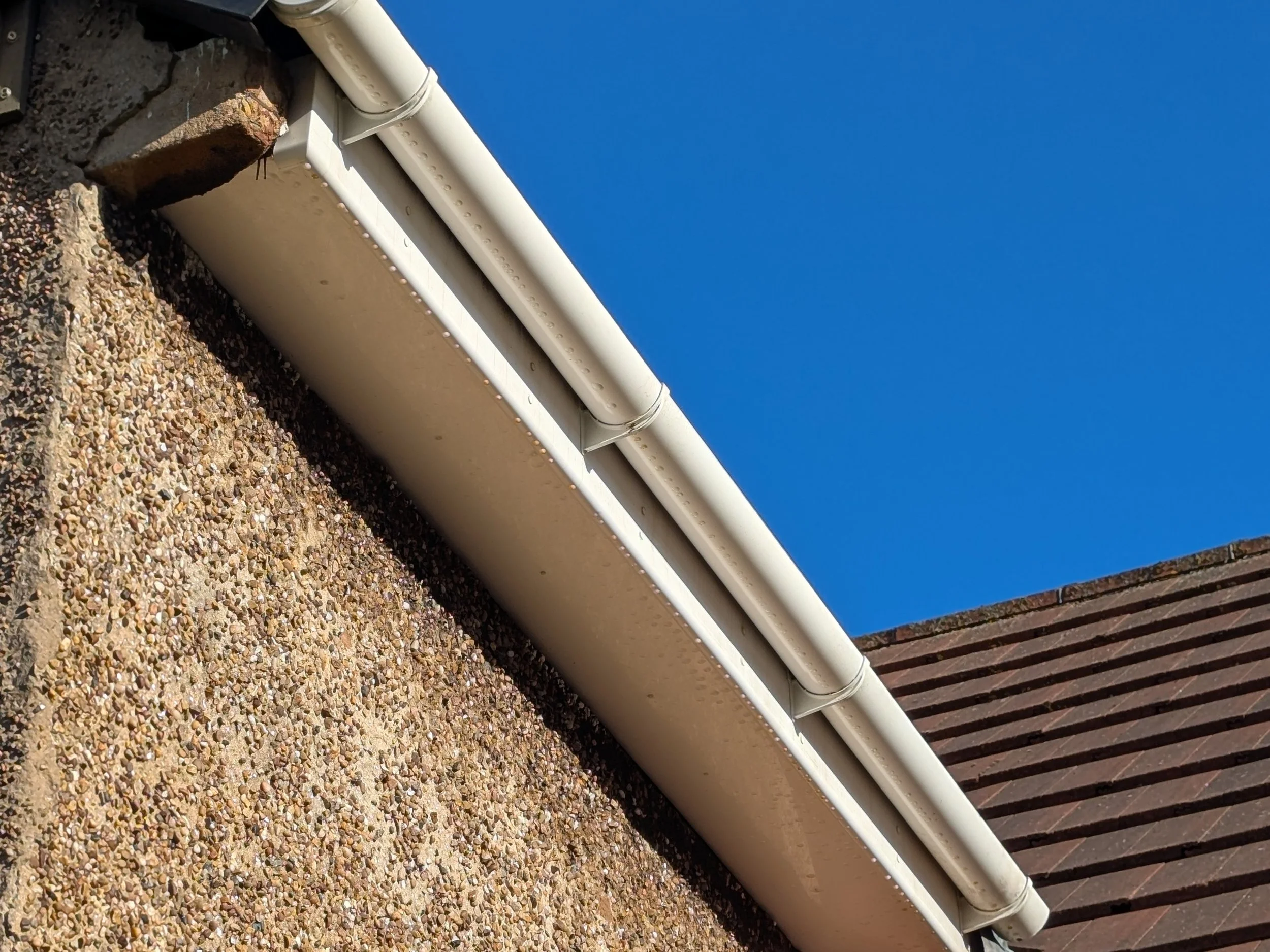 Close-up view of the edge of a roof with white gutters that have just been cleaned by Jet Set Washe