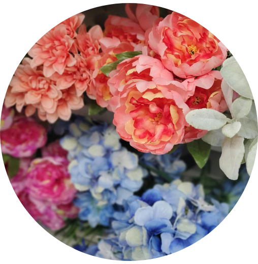A vibrant bouquet featuring pink, peach, blue, and white flowers, including roses and hydrangeas, arranged in a lush and elegant display.