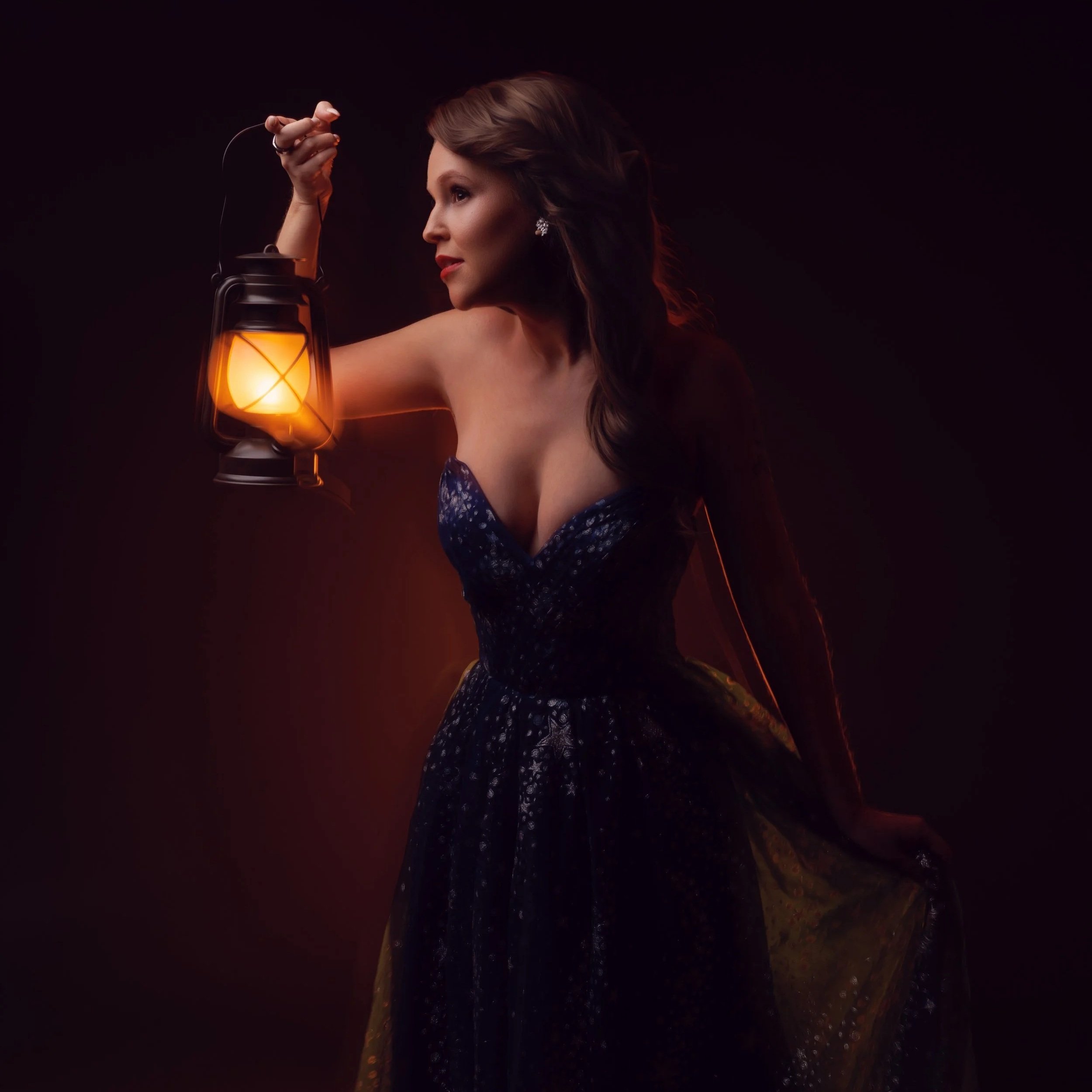 A woman with long, wavy hair in a strapless dark blue dress, holding a vintage lantern with warm light against a dark outdoor background at sunset.