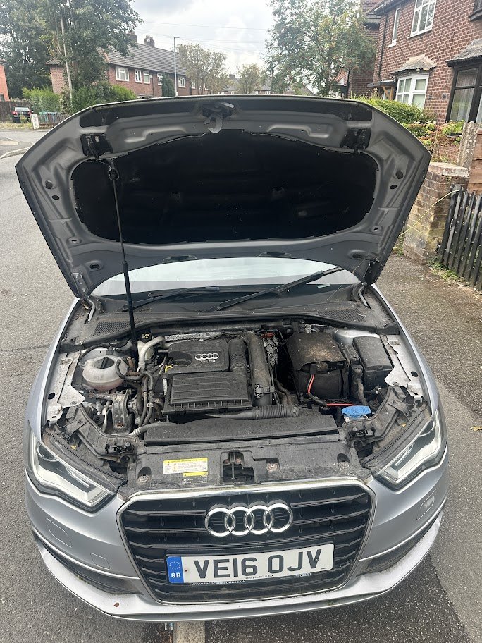 Front view of an Audi car with open hood parked on the street.