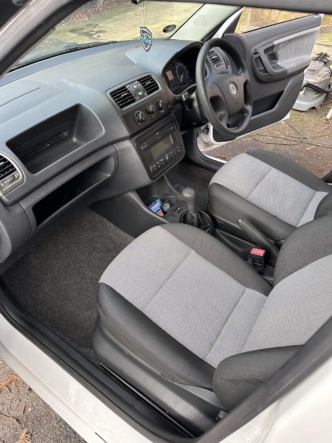 Interior of a Volkswagen vehicle, showing the front seats, steering wheel, dashboard, and center console with radio and controls.