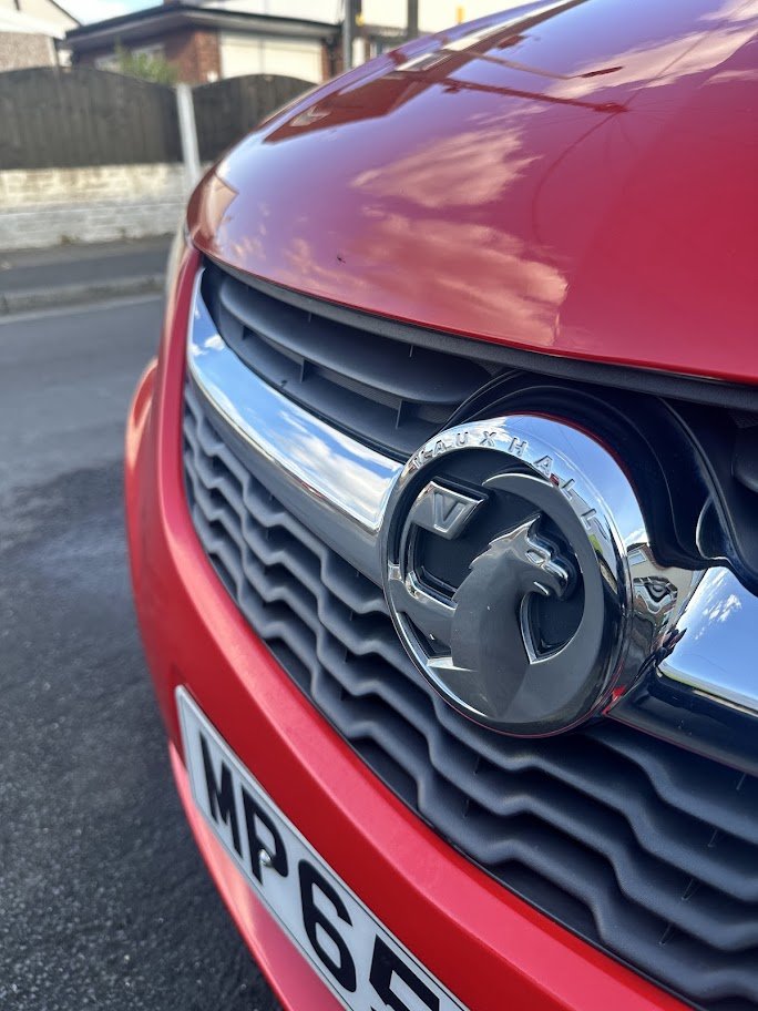 Close-up of the front of a red Vauxhall car showing the Vauxhall badge on the grille.