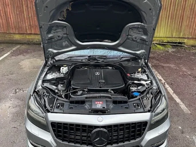 Front view of a silver Mercedes-Benz car with the hood open, showing the engine compartment.