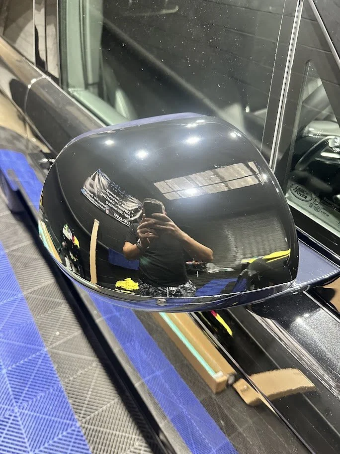 side mirror of a black car, with a garage or workshop ppf protection