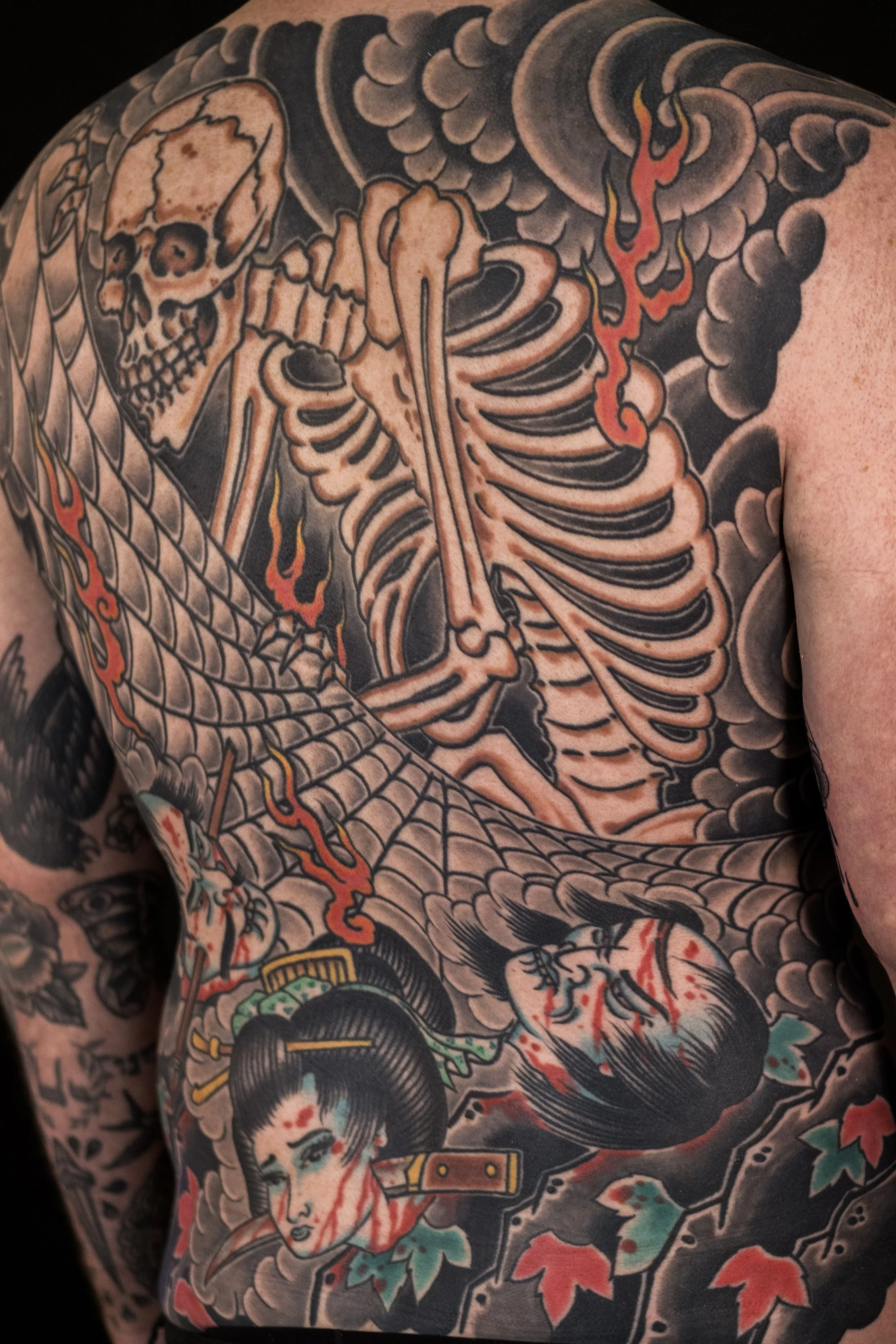 Traditional Japanese tattoo featuring a female figure with a traditional hairstyle, surrounded by colorful floral patterns and flowing elements.