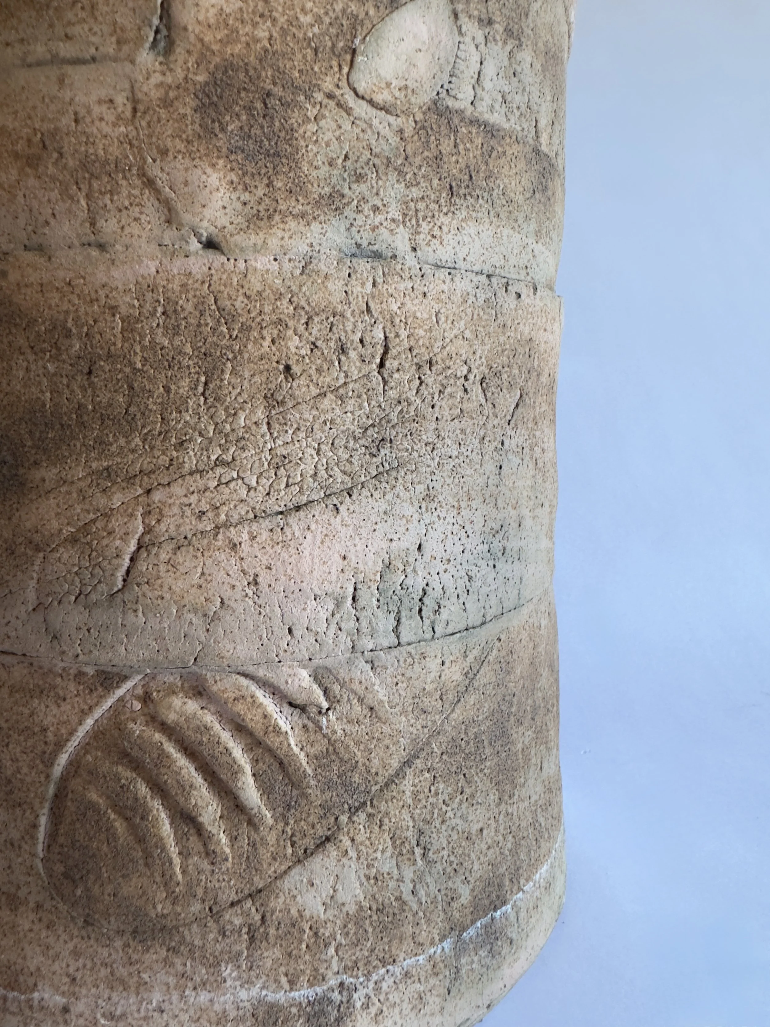 Close-up of aztec style vase with engraved designs and weathered texture, partially visible on a light-colored surface.