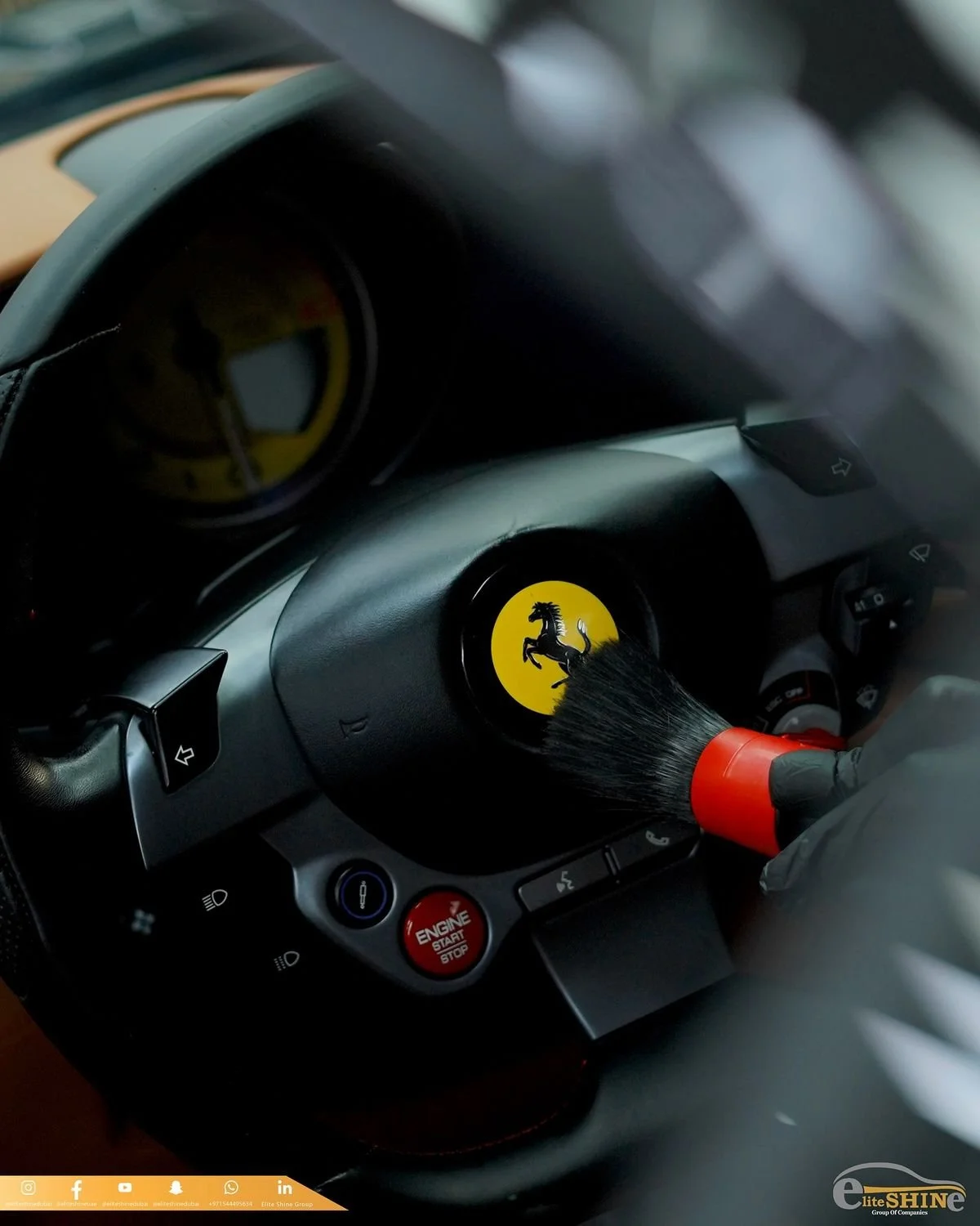 Inside a Ferrari car, cleaning the steering wheel with a brush.