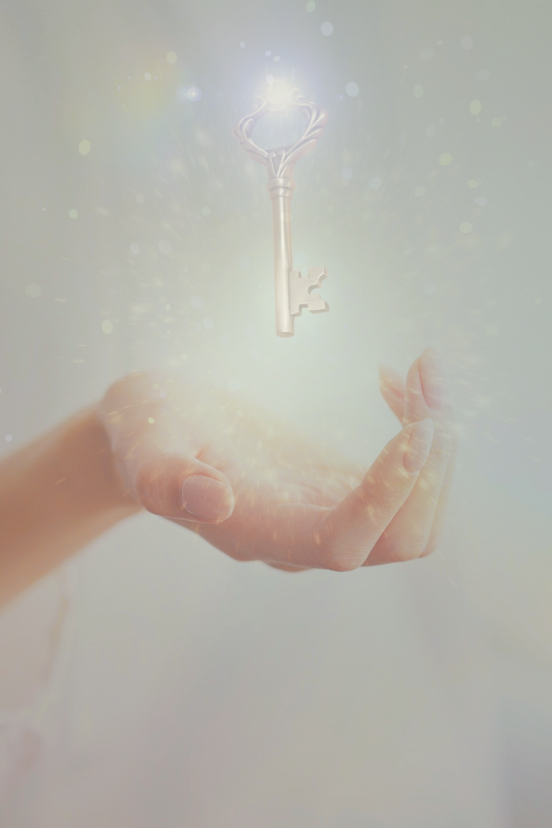 A hand holding a glowing, magical key floating in mid-air with light and sparkles surrounding it.