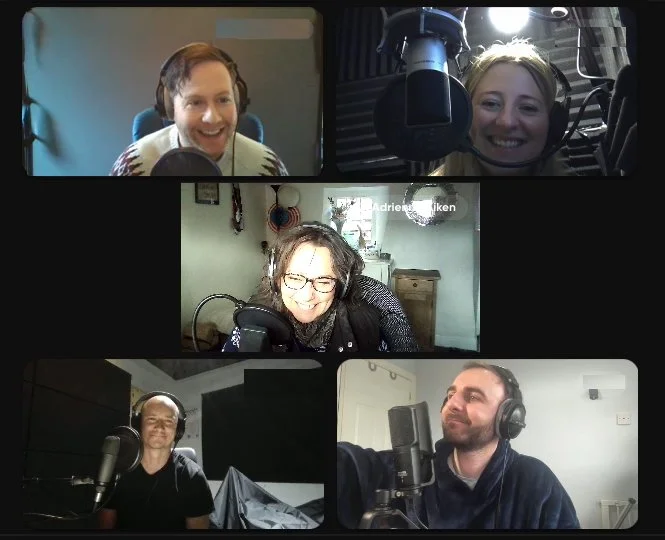 Five people participating in a virtual podcast or video call, each with a microphone and headphones, smiling and engaging in conversation.
