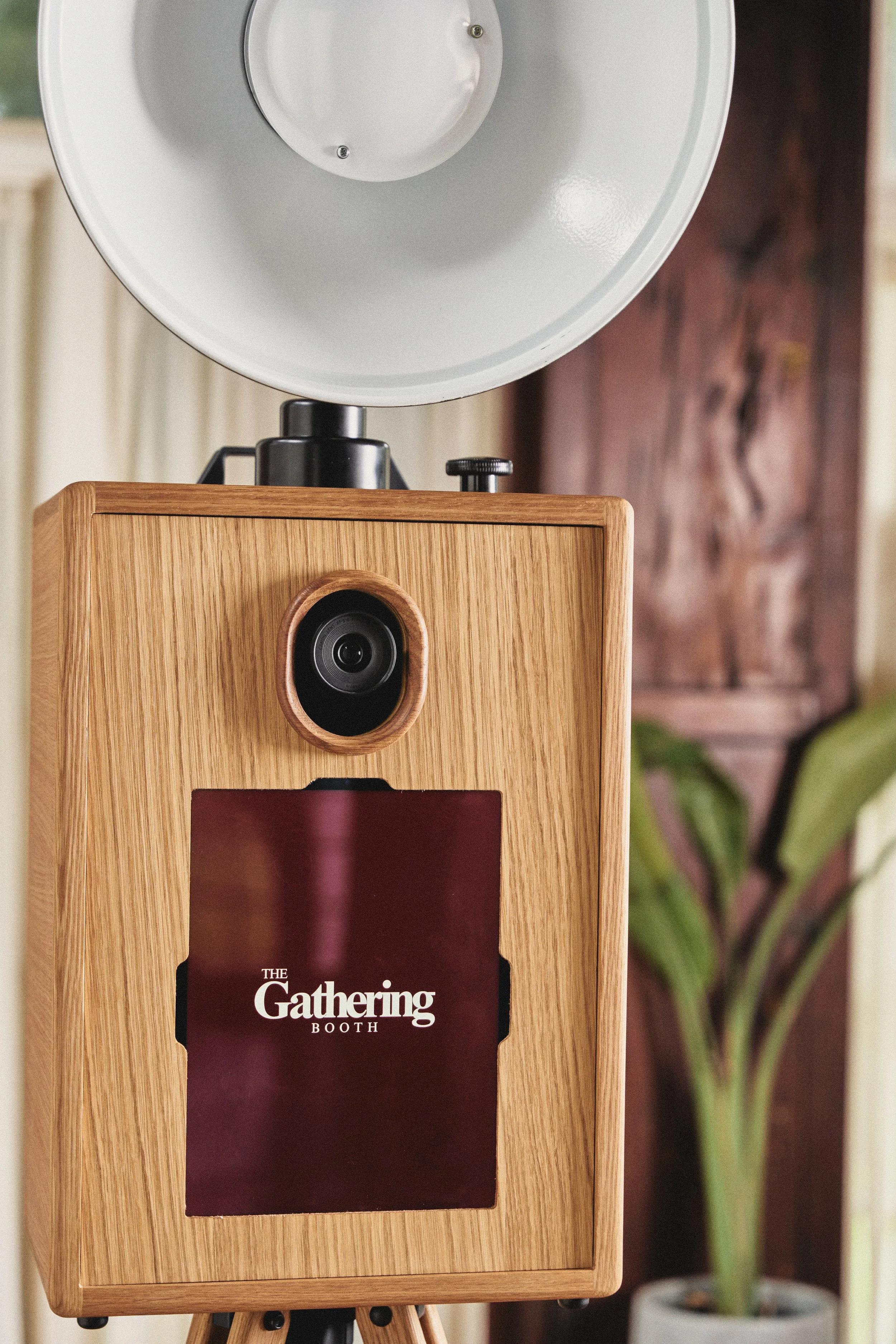 A photo of a wooden photo booth with a speaker on top, displaying a sign that says 'The Gathering Booth.'