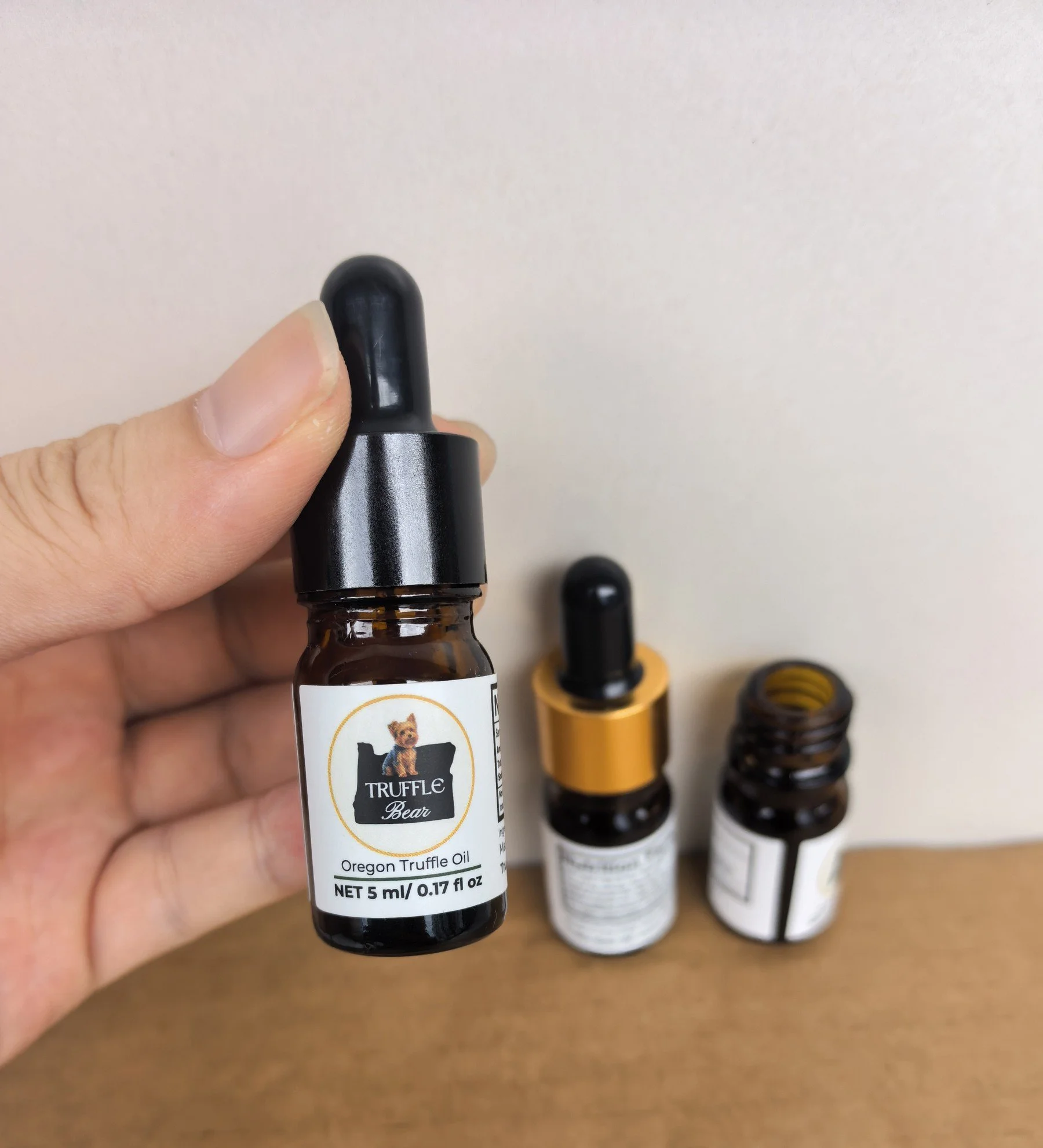 A hand holding the 5ml Truffle Bear Oil dropper bottle of real Oregon truffle oil