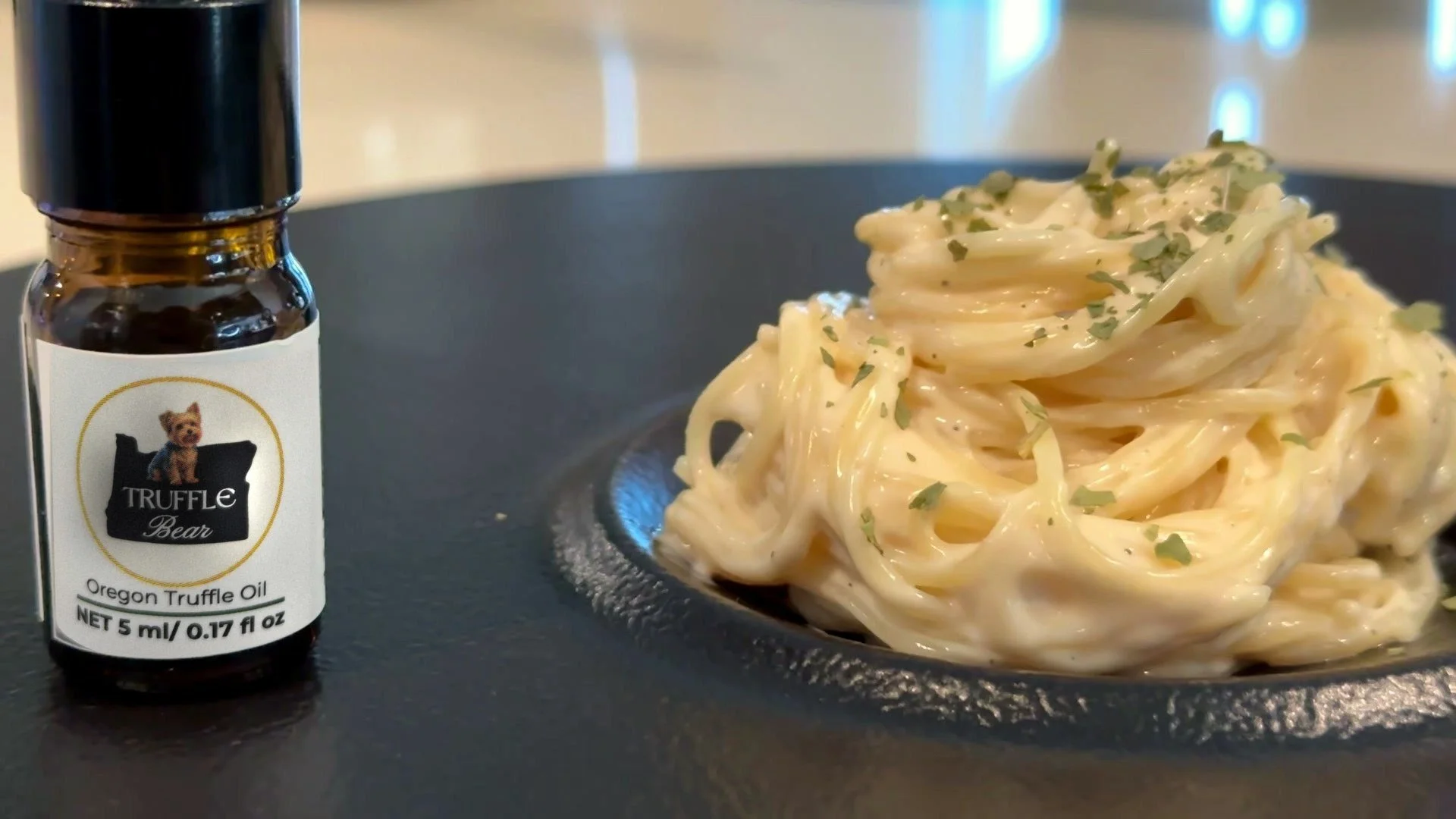 Truffle Bear oil bottle beside a bowl of creamy truffle pasta