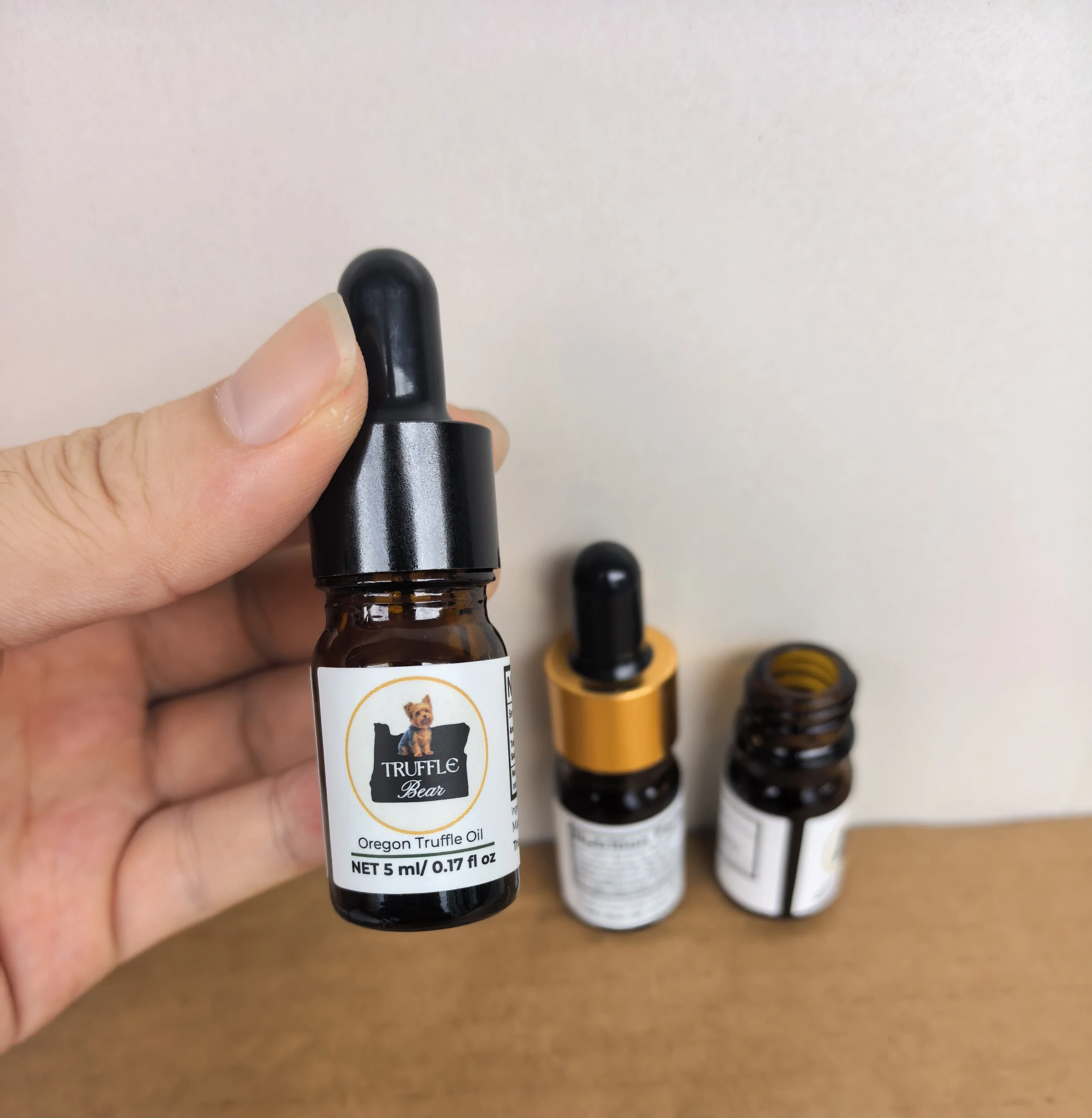 A hand holding a Truffle Bear oil dropper bottle