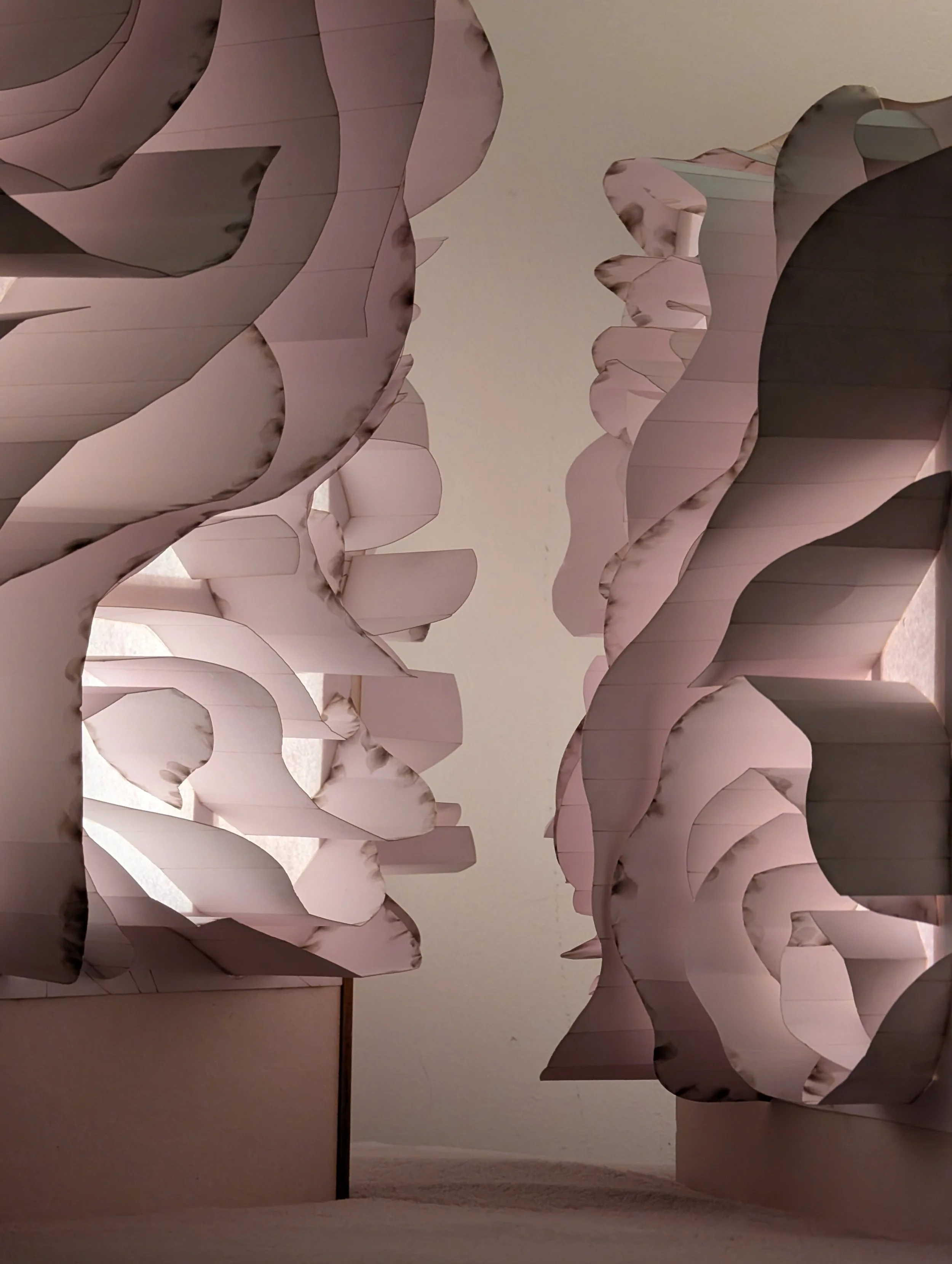 A close-up view of a decorative wall with layered, wavy, pinkish panels that resemble flower petals, creating a textured, floral-inspired design.
