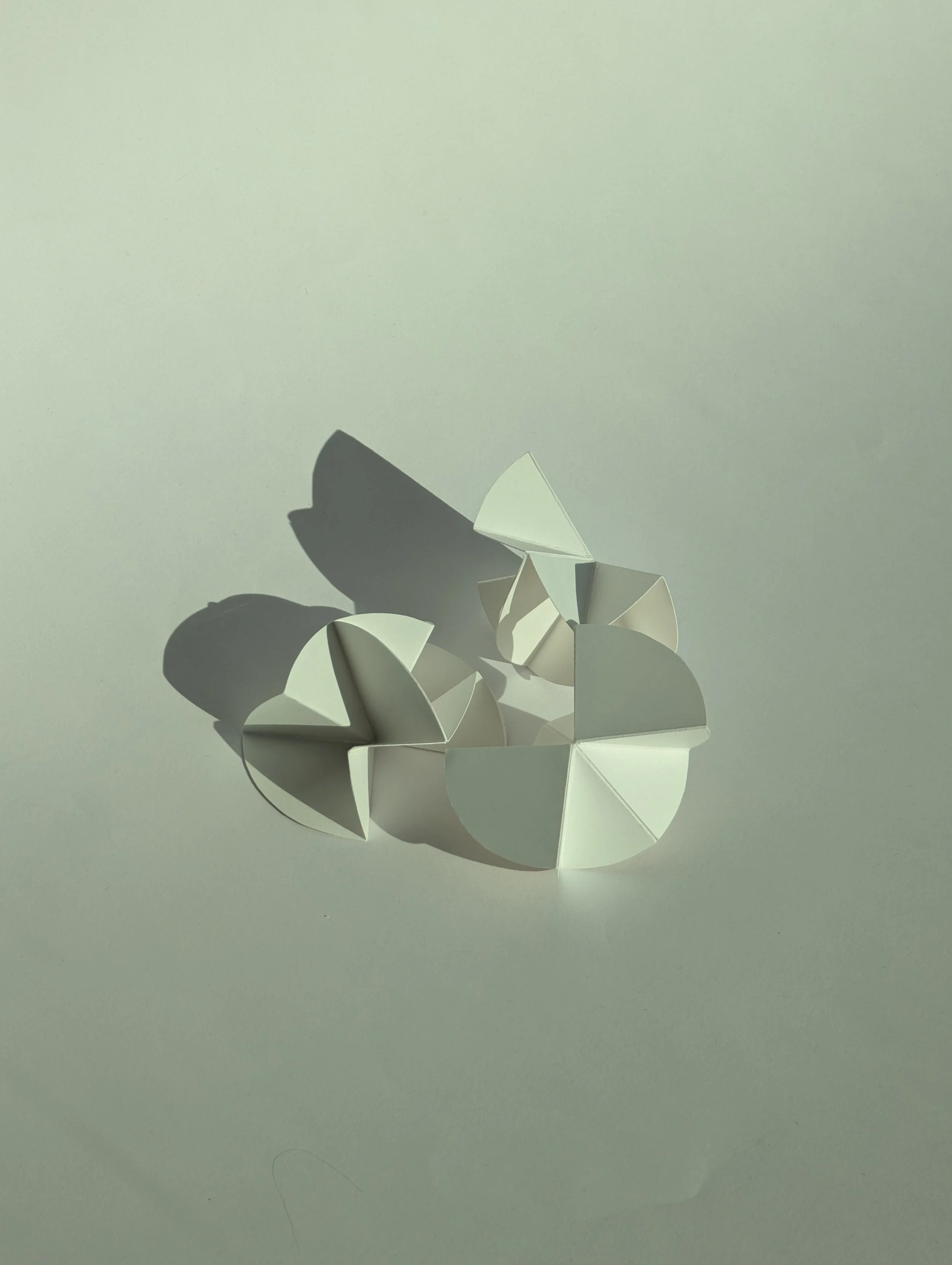 A white origami butterfly with folded wings on a light surface, casting shadows.