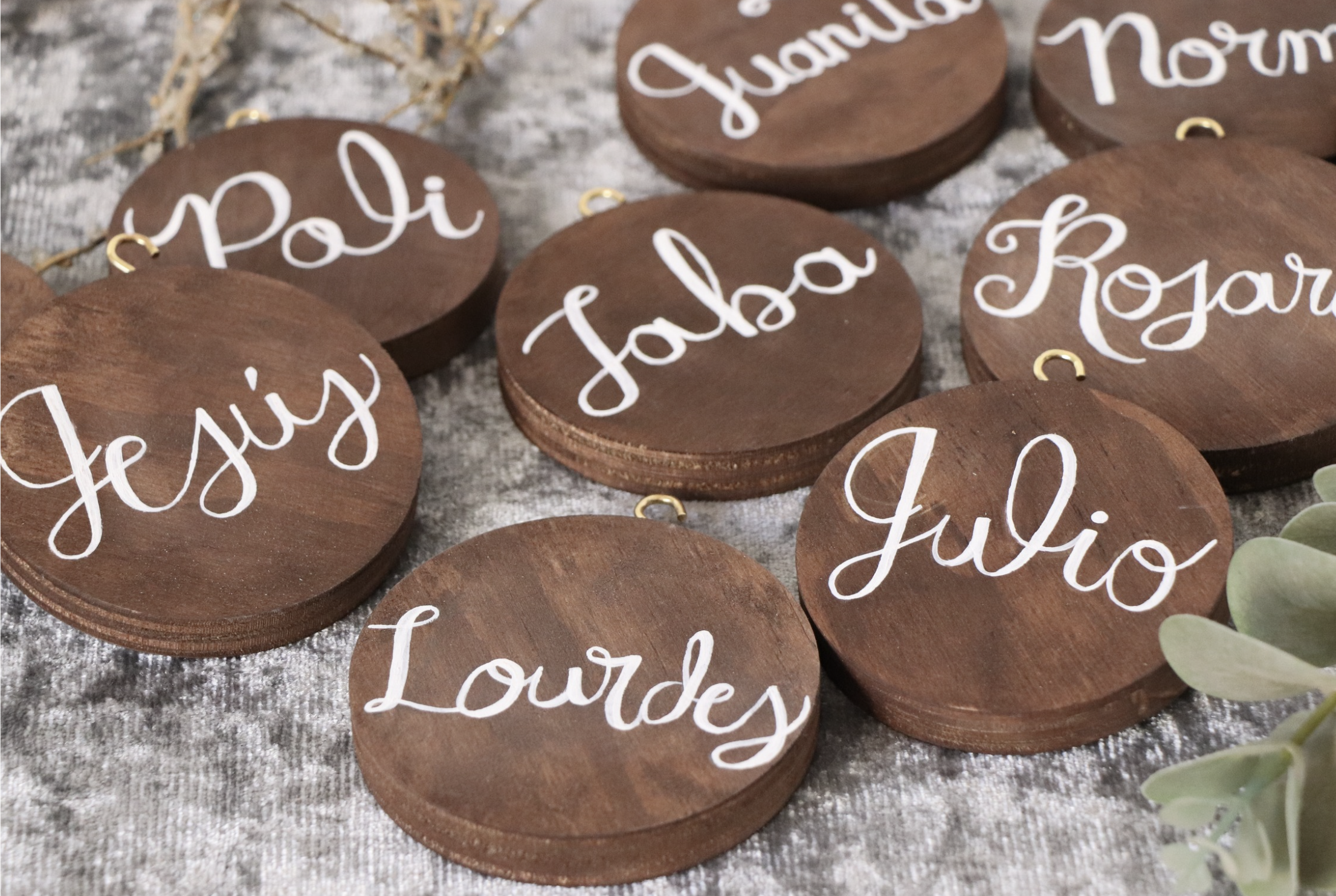Round wooden ornaments with white cursive writing of words like 'Party,' 'Laughter,' 'Joy,' 'Love,' 'Mom,' and 'Grandma'.