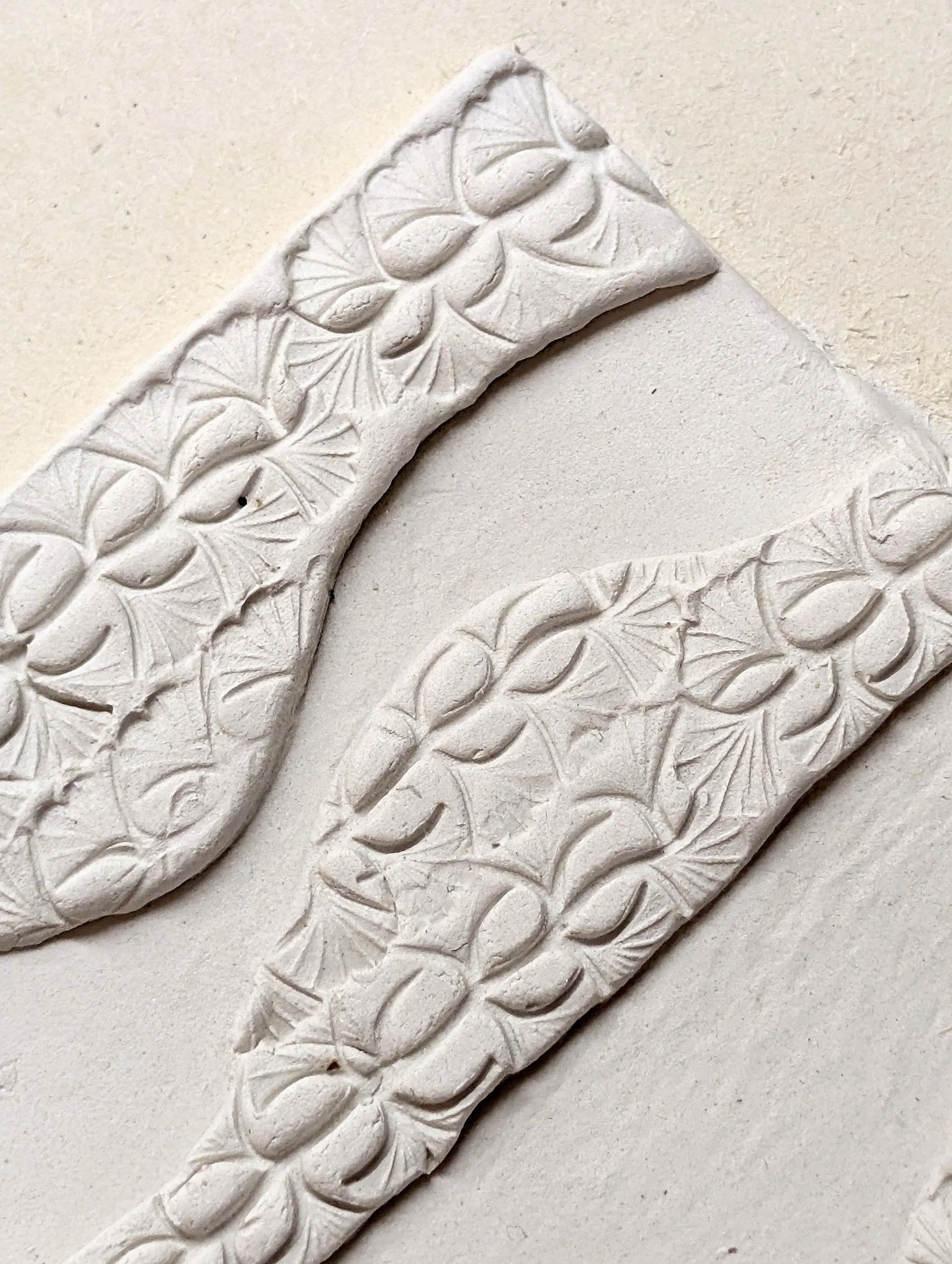 Close-up of an intricately carved white ceramic tile with floral and geometric patterns.