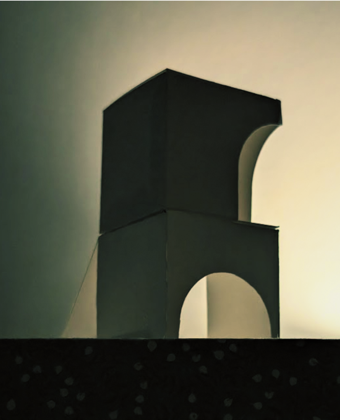 Stack of large cardboard boxes, some with arches cut out, against a plain light-colored wall.
