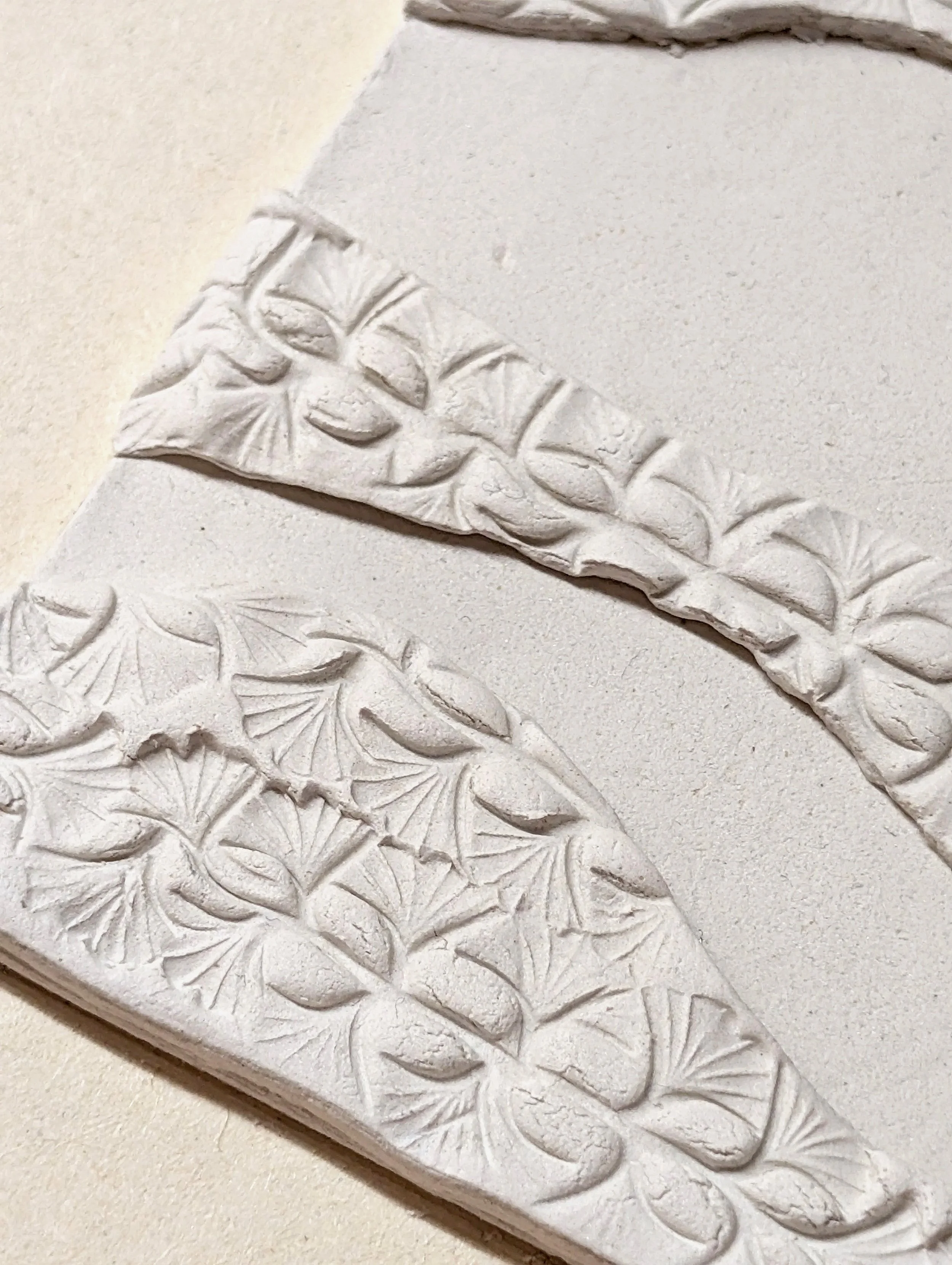 Close-up of carved white stone with a textured leaf pattern.