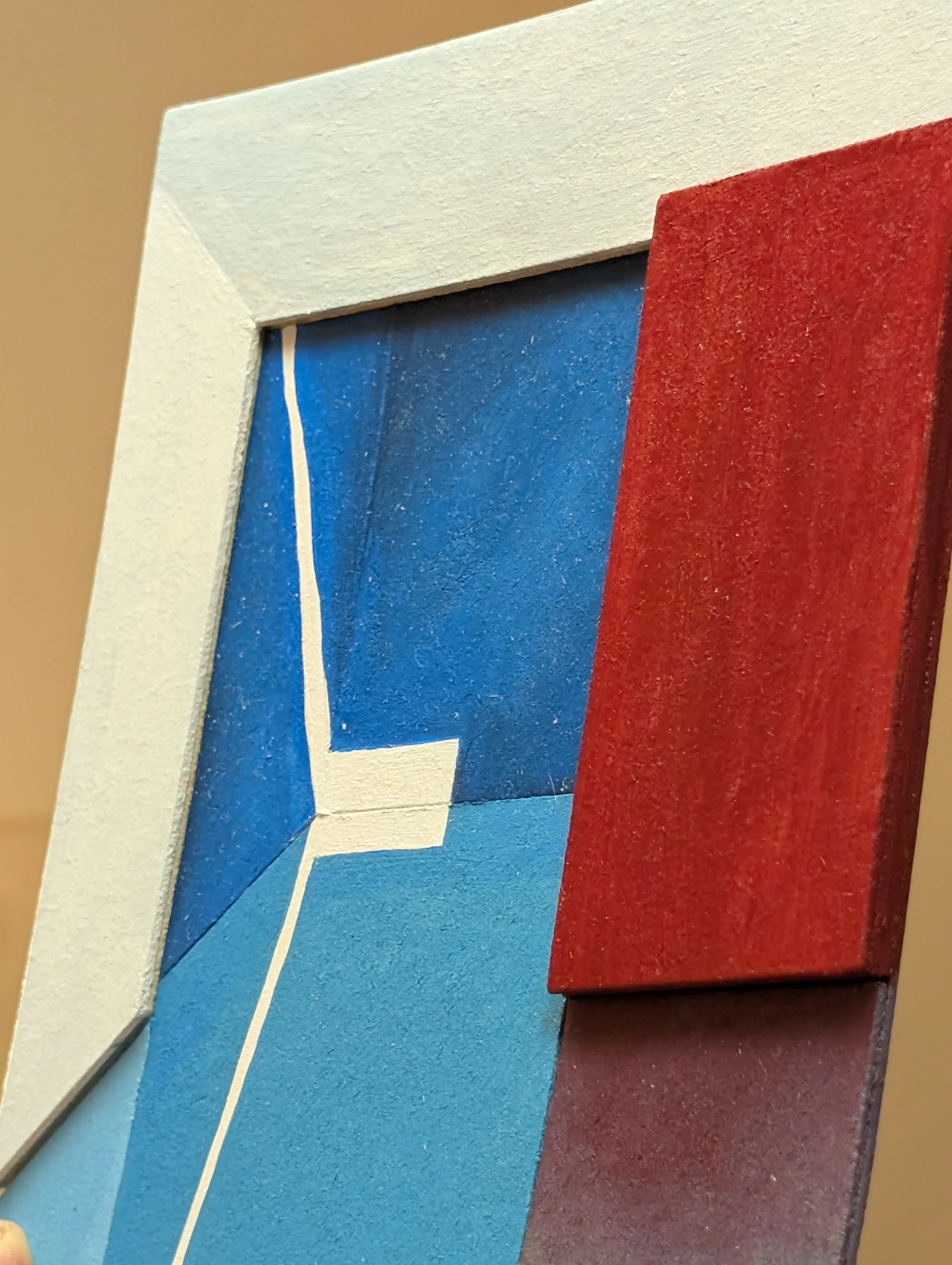 Close-up of a colorful abstract painting with geometric shapes in blue, red, white, and brown colors.