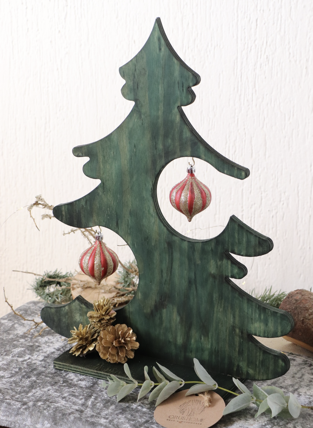 Decorative wooden Christmas tree with hanging ornaments, pinecones, and greenery.