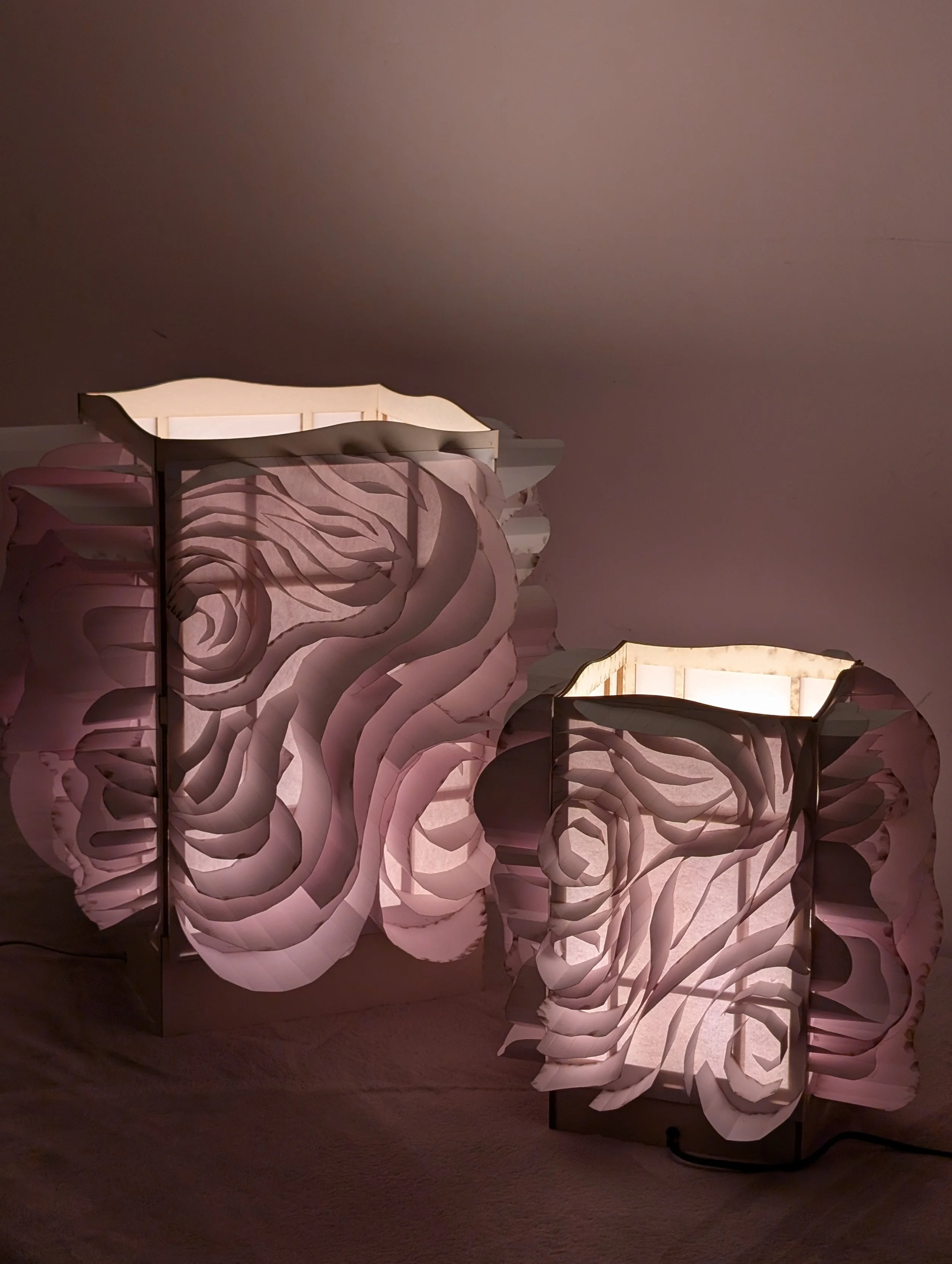Decorative white paper lamp with swirling petal-like shapes, illuminated and casting a soft glow in a dimly lit room.