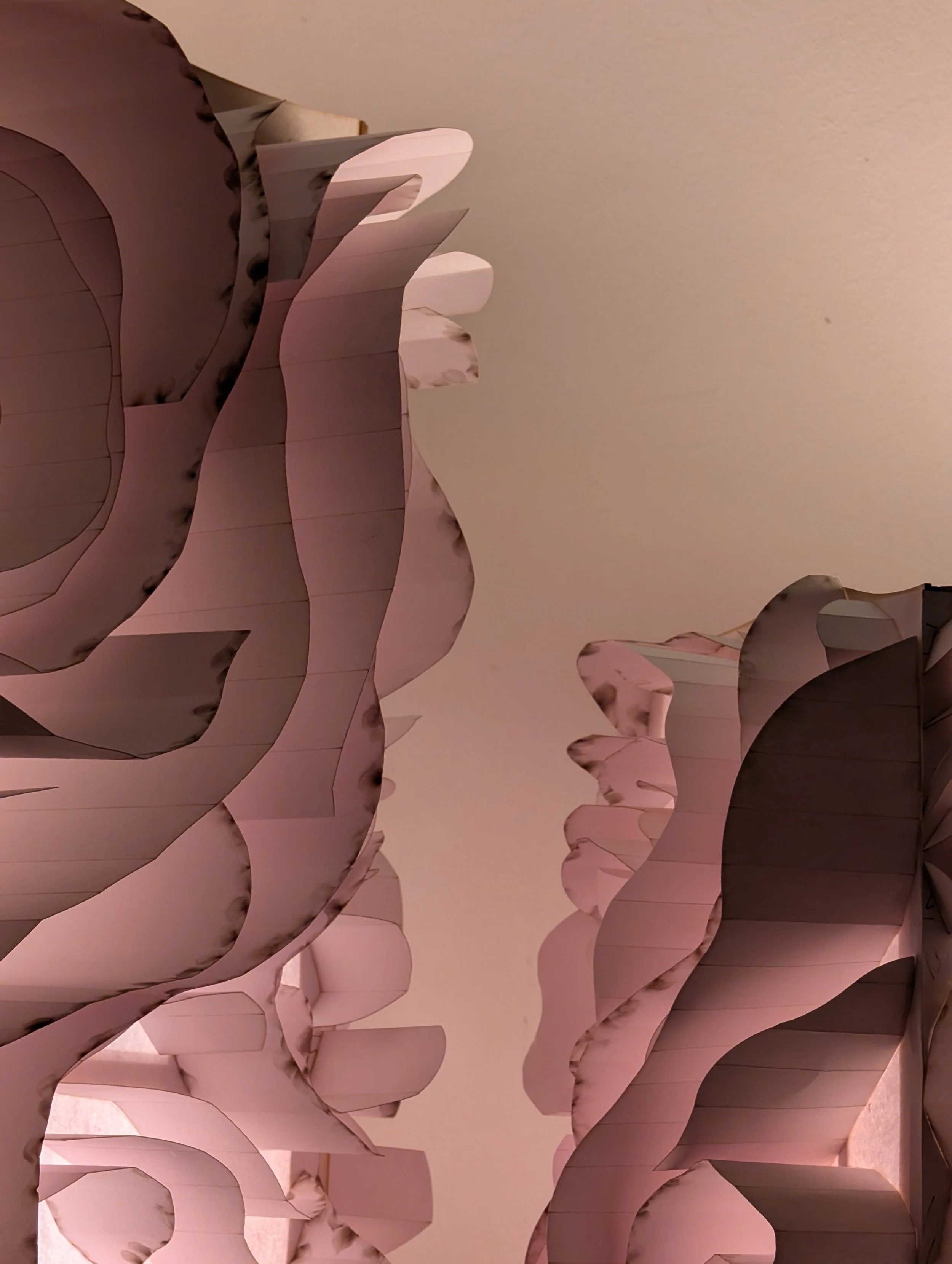 Close-up of layered pink and white paper or cardboard decorative cutouts arranged in a repeating pattern.