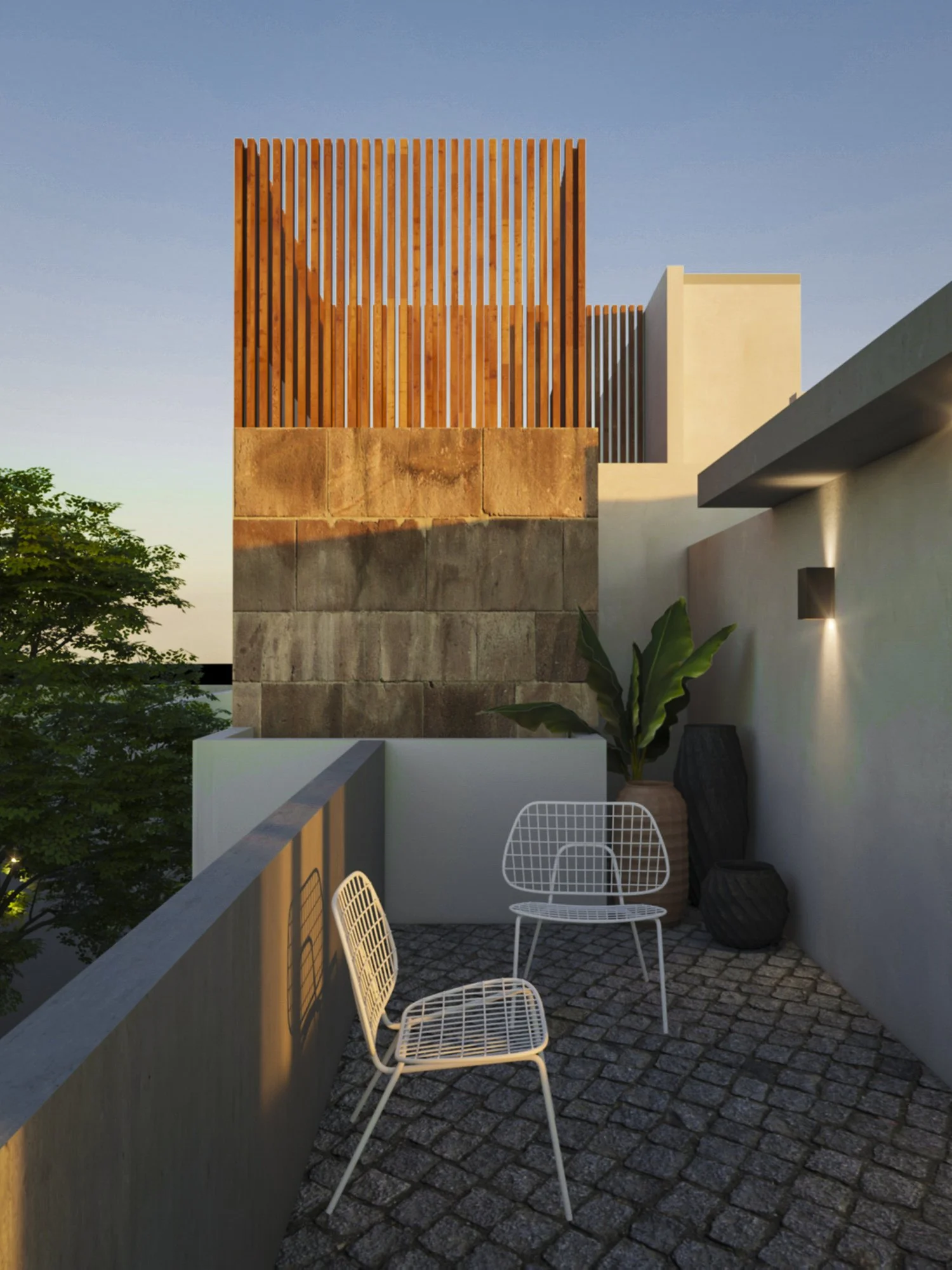 An outdoor balcony with white wire chairs, potted plants, and a stone-tiled floor, with modern buildings in the background during dusk.
