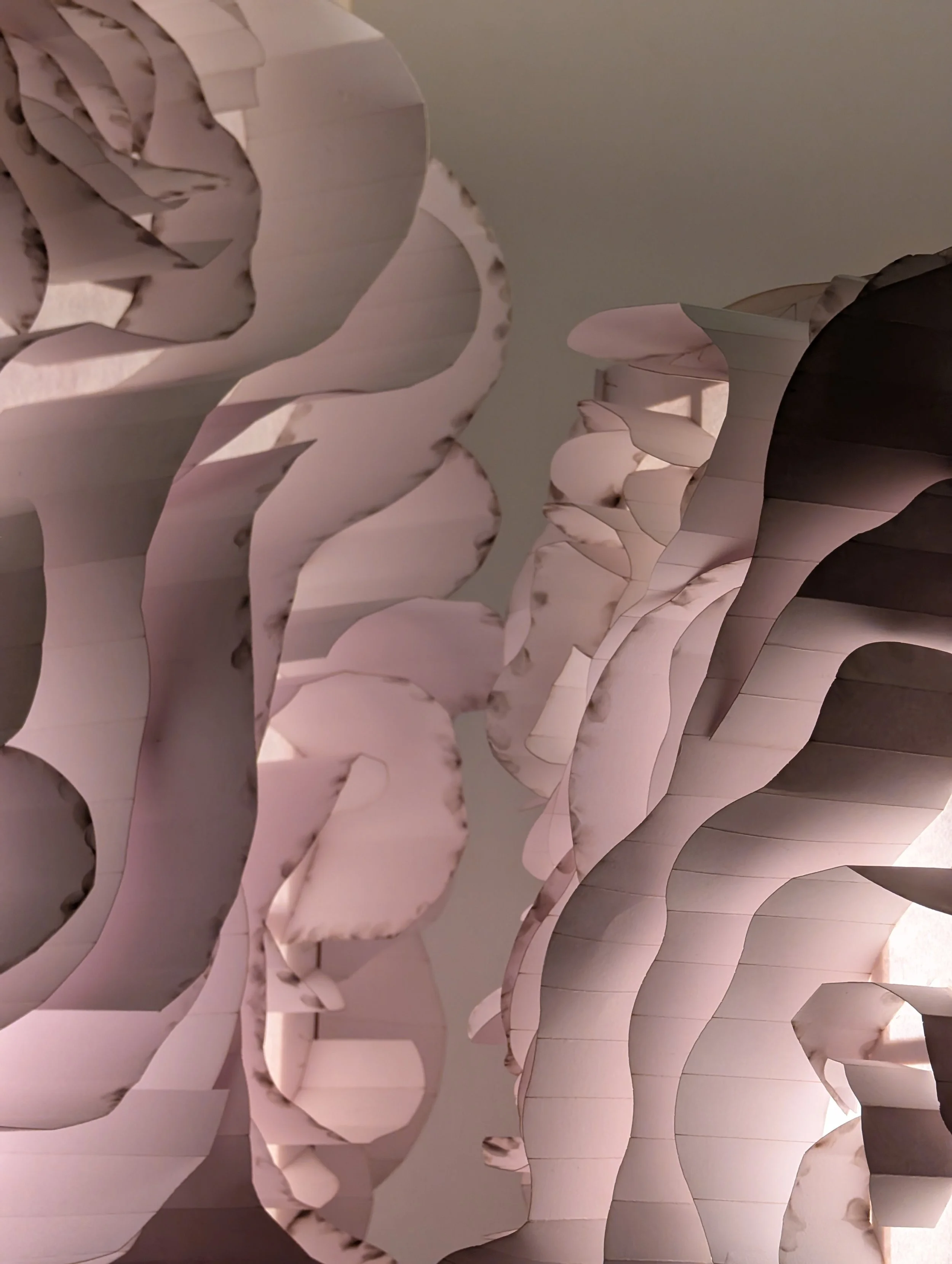 Close-up view of layered, wavy, white decorative panels with marble-like veining, creating an abstract pattern.