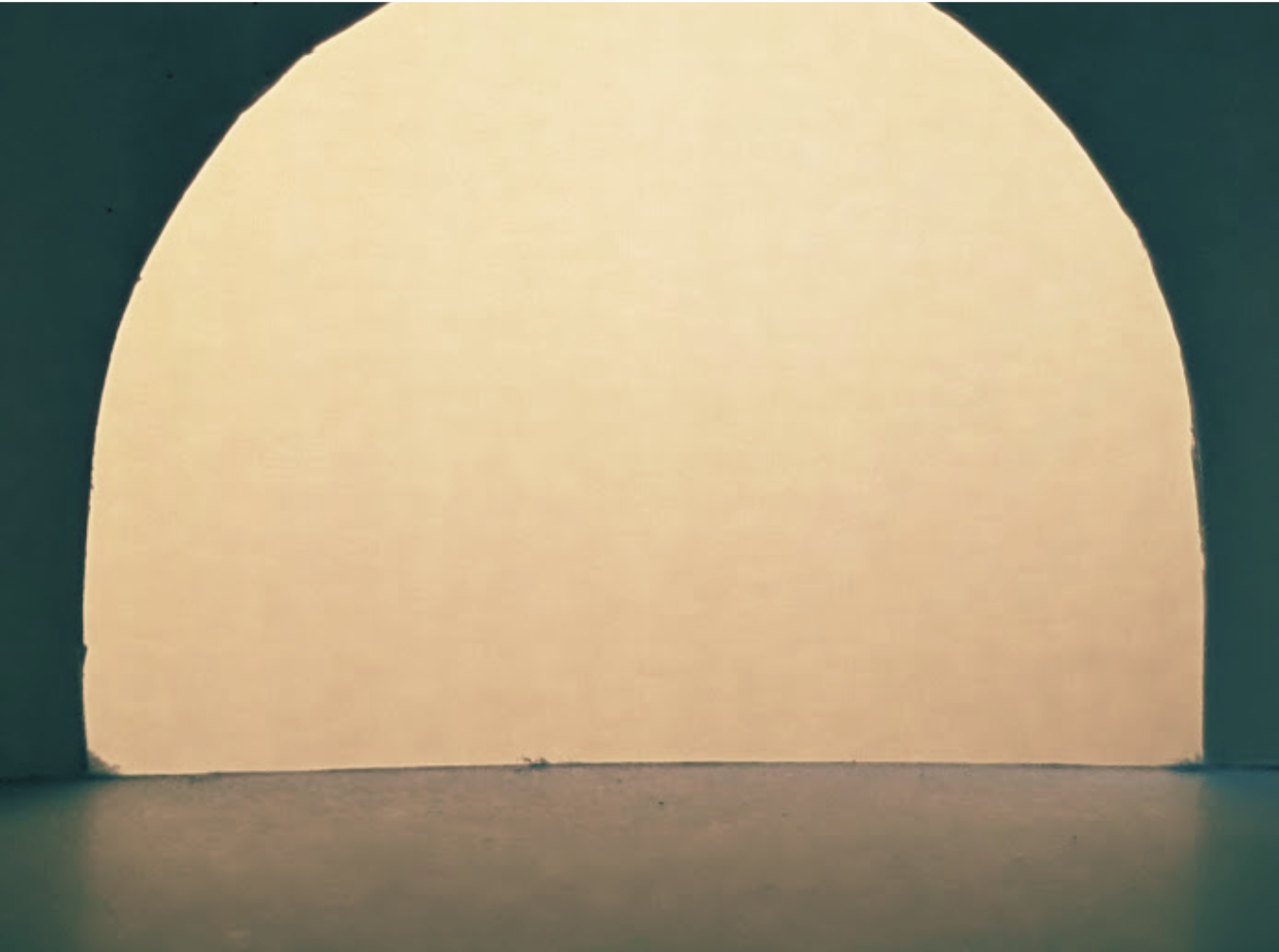 A close-up view of a paper lantern or light fixture with a smooth, rounded surface emitting a soft, warm glow against a dark background.