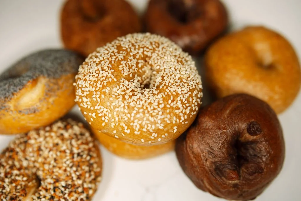 Close-up of assorted bagels with sesame seeds, poppy seed bagel, and plain bagel.