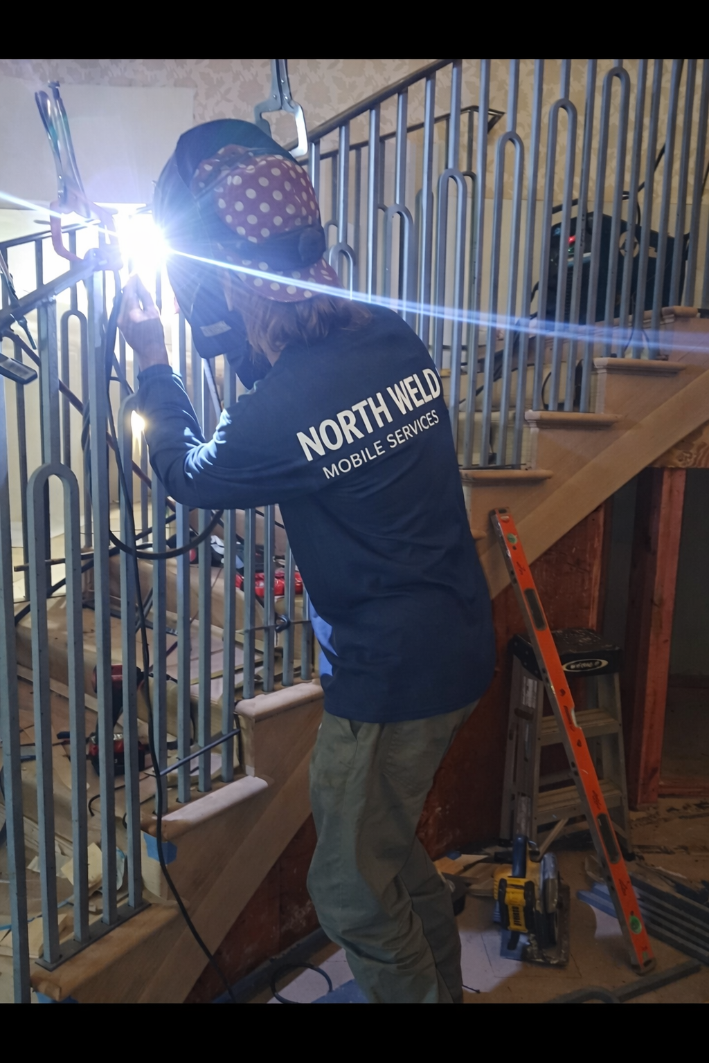 A person welding metal railing on a staircase in a construction setting.