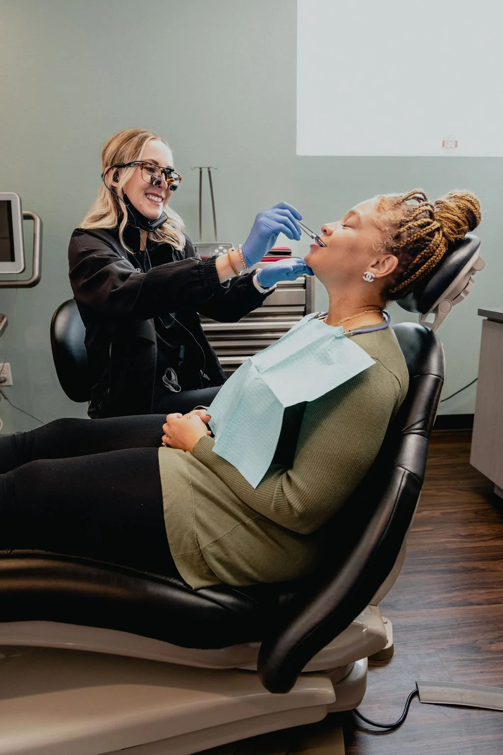 Dentist performing a dental procedure on a patient who is reclining in a dental chair.