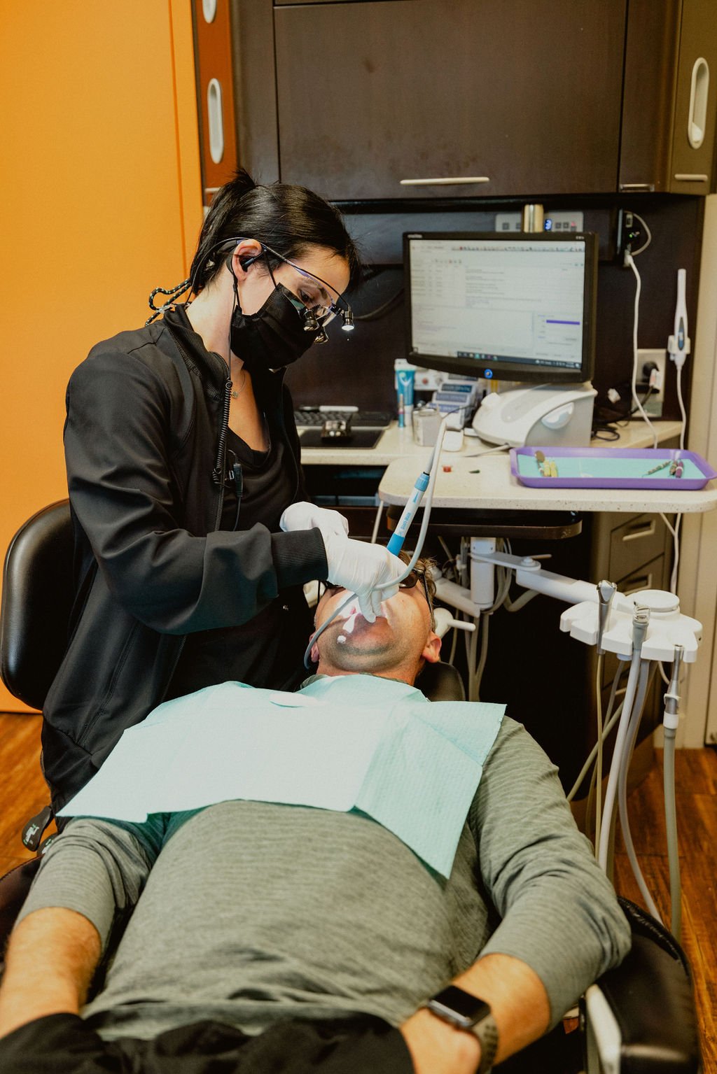 Dentist or dental hygienist performing a dental procedure on a patient in a dental office or clinic.