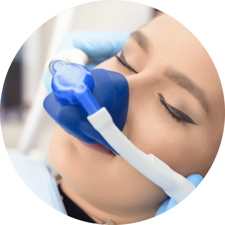 A woman in a medical setting wearing a blue oxygen mask with a white strap, with her eyes closed.