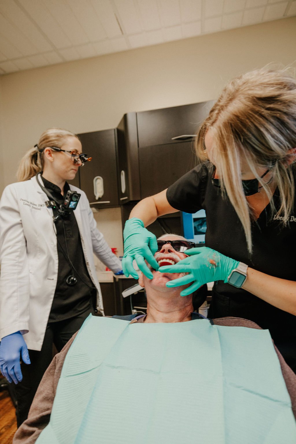 Dentist and assistant examining a patient's mouth in a dental office.