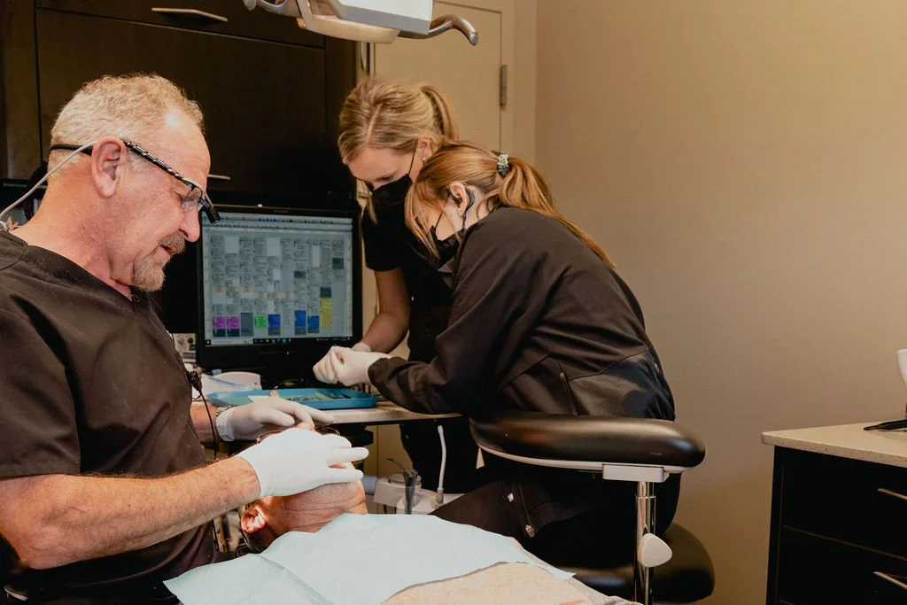 Dentist and assistants working on a patient in a dental office.