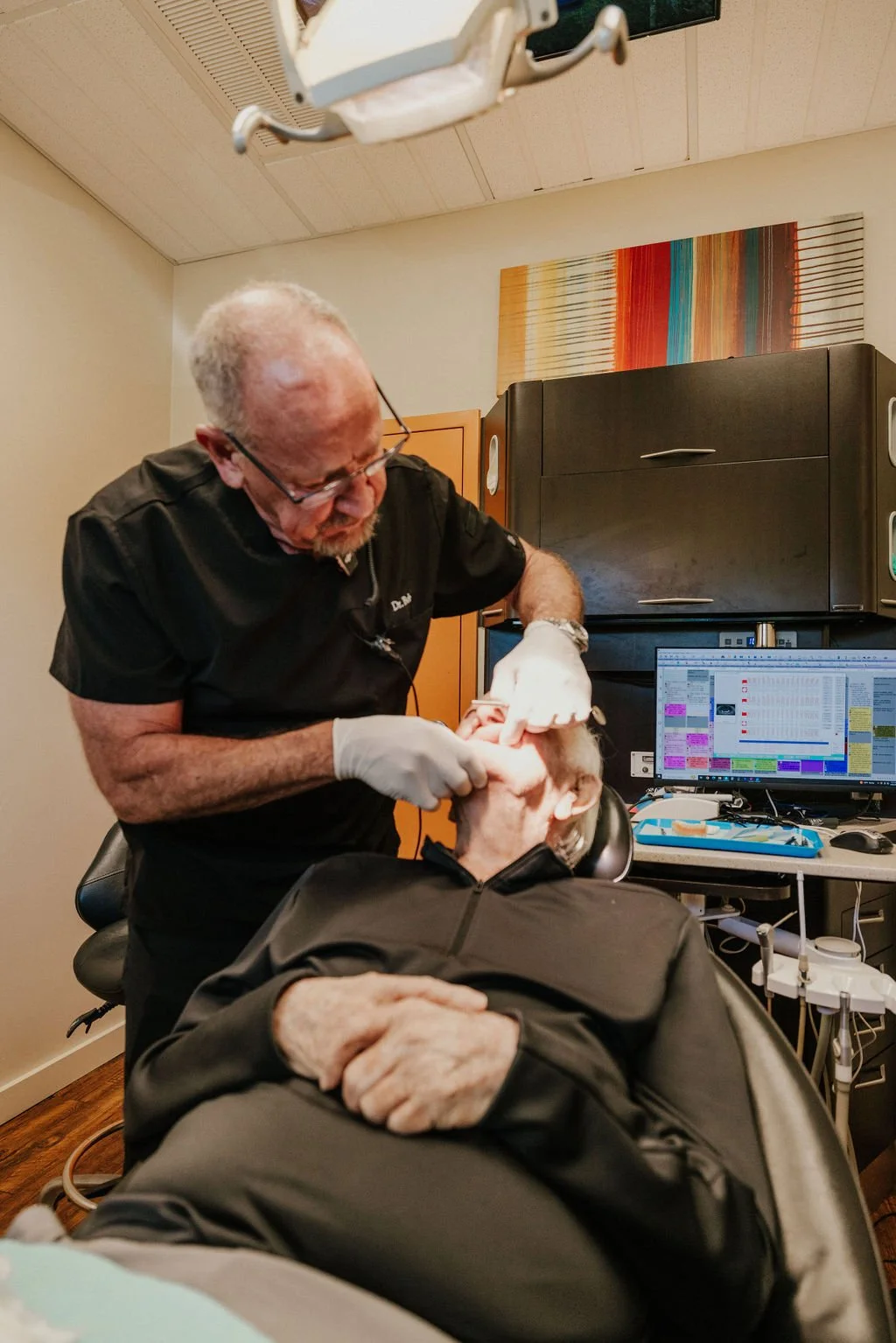 A doctor performing a dental or oral examination on an elderly patient in a medical office.