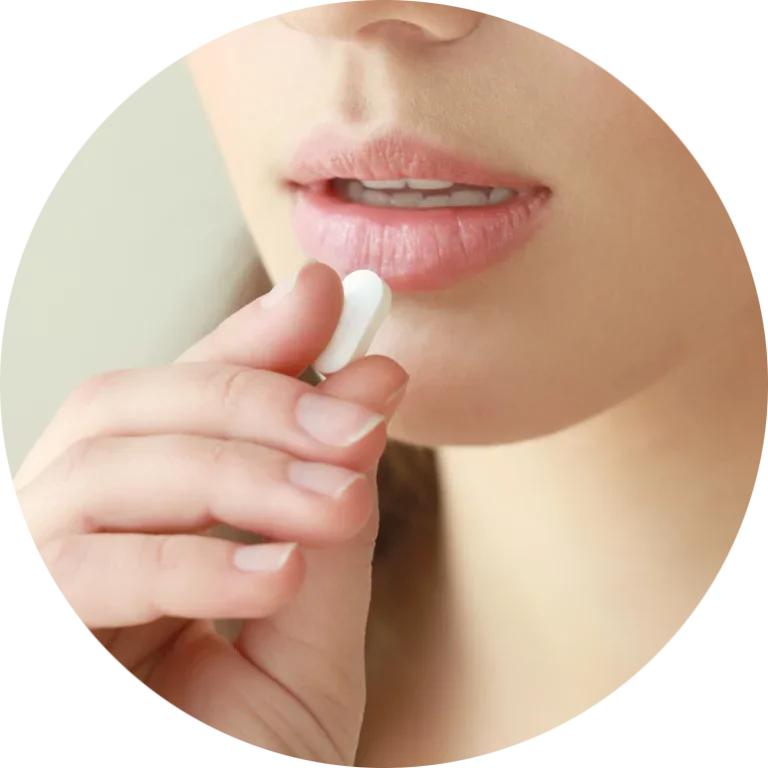 Close-up of a person holding a white pill near their lips.