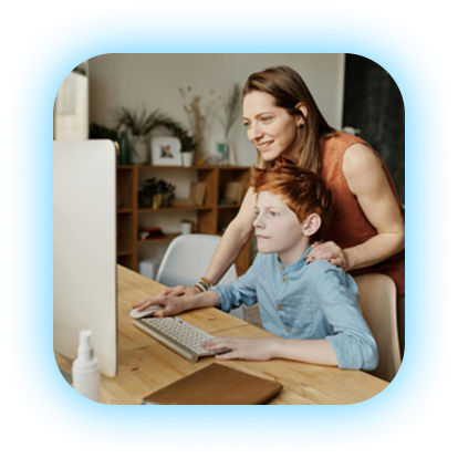 A woman helping a young boy with a computer at a desk in a home setting.