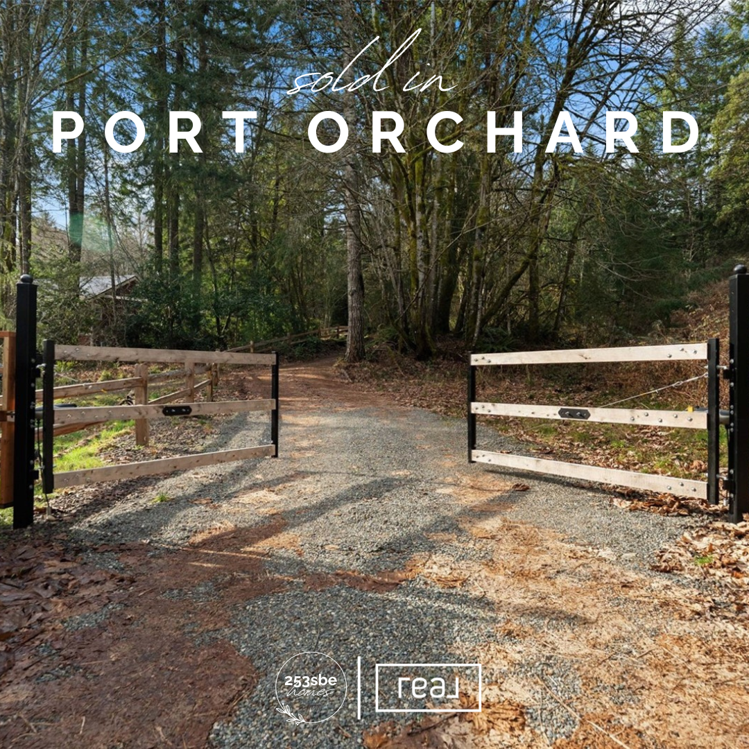 A gravel driveway with a wooden gate on each side, leading into a wooded area with trees and lush greenery.
