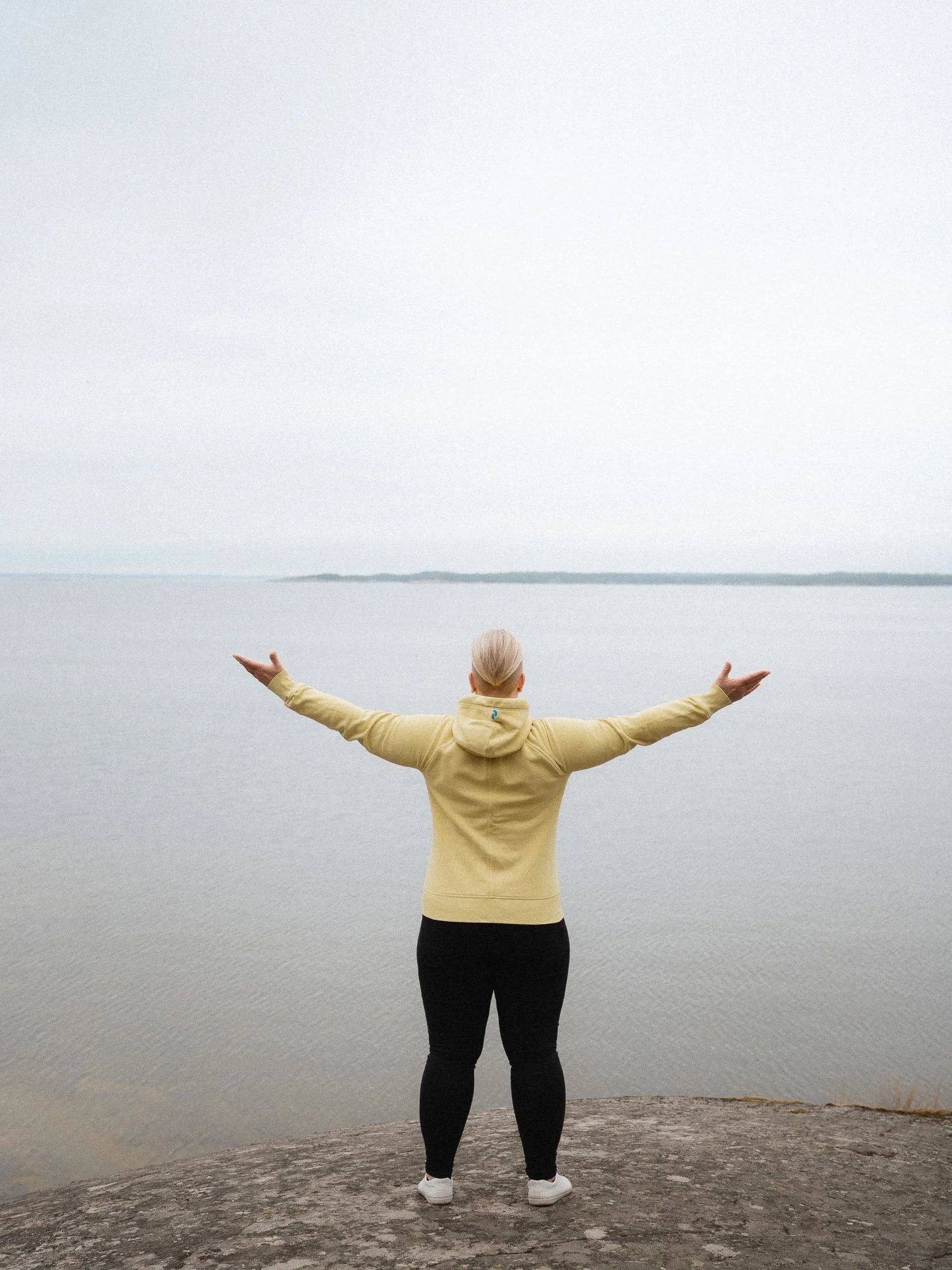 Työelämän hermostocoach Minna Fronden kädet avoimena rantakalliolla.