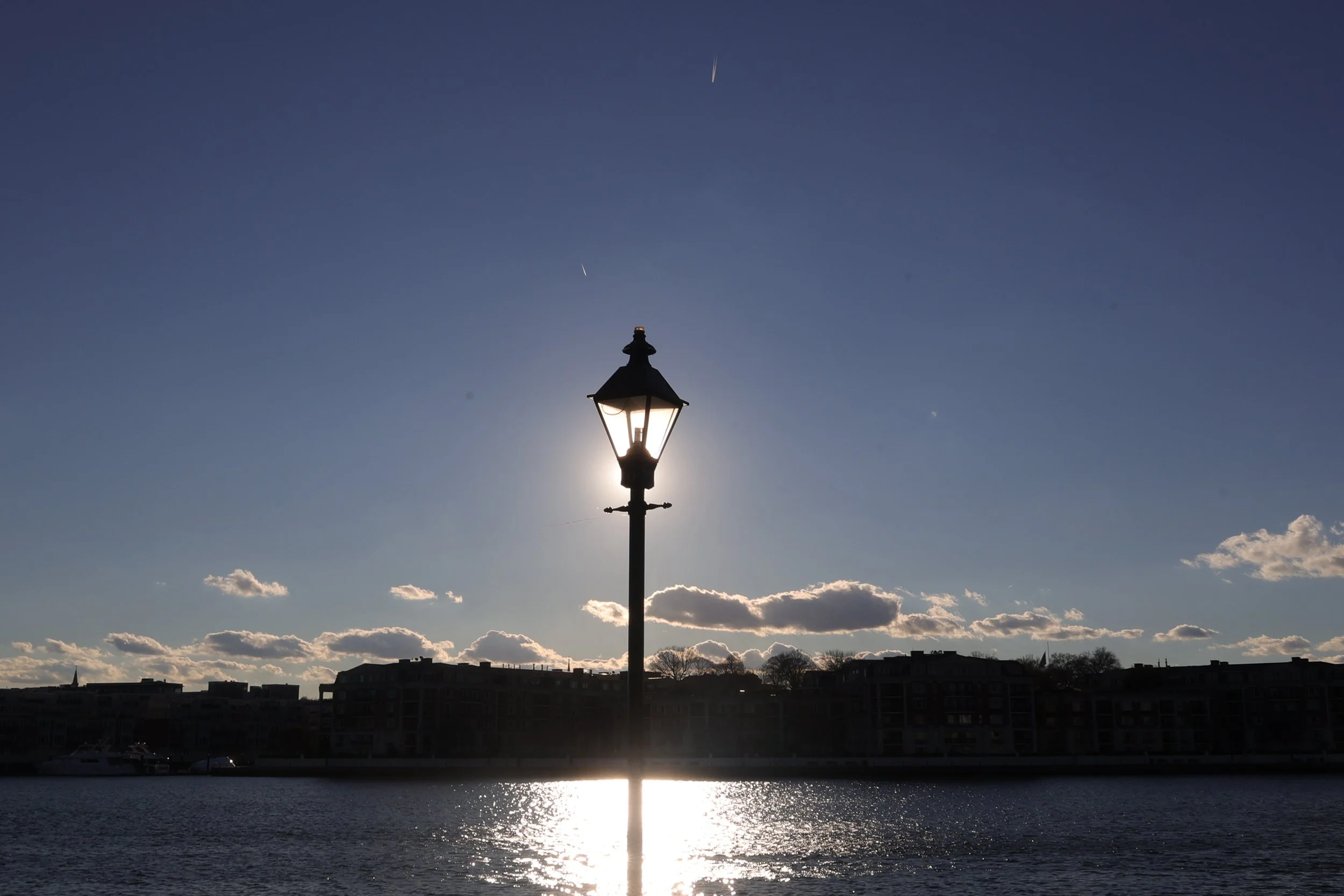 Sunset over a body of water with a lamp, and a wide open sky