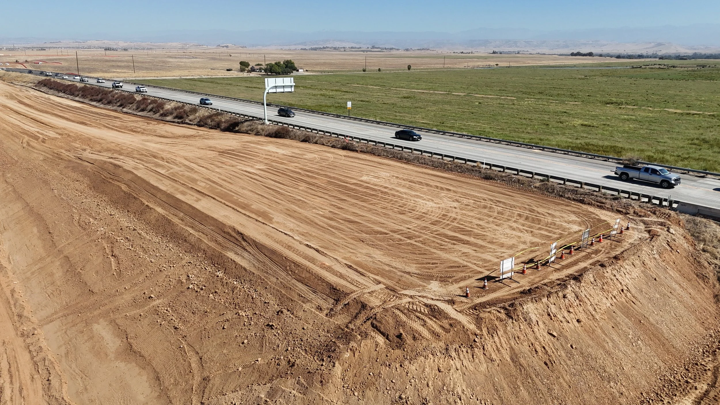 A compacted mound of dirt on the left of the Avenue 11 bridge.