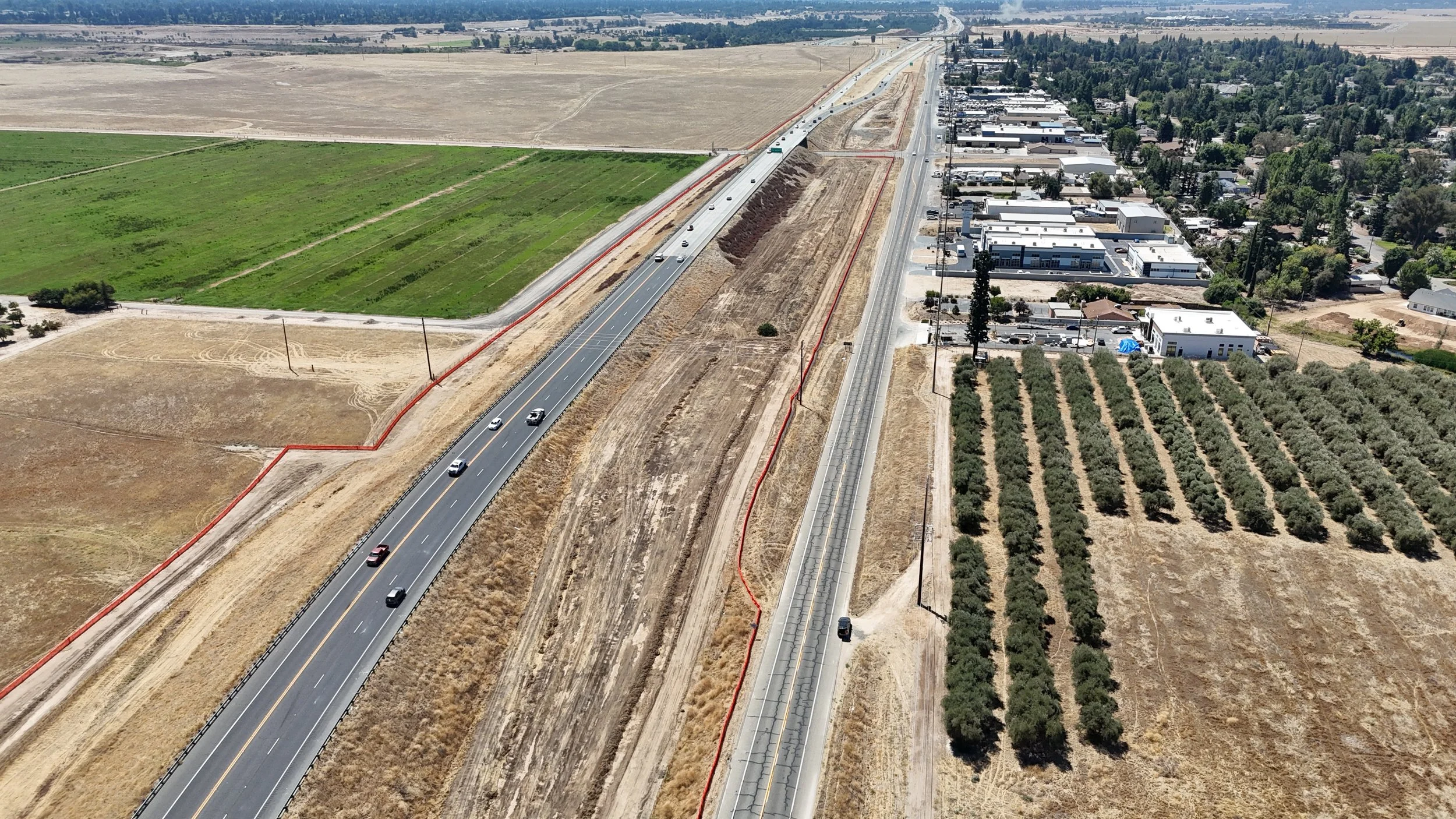 Vertical road with orange fencing on the left and right.
